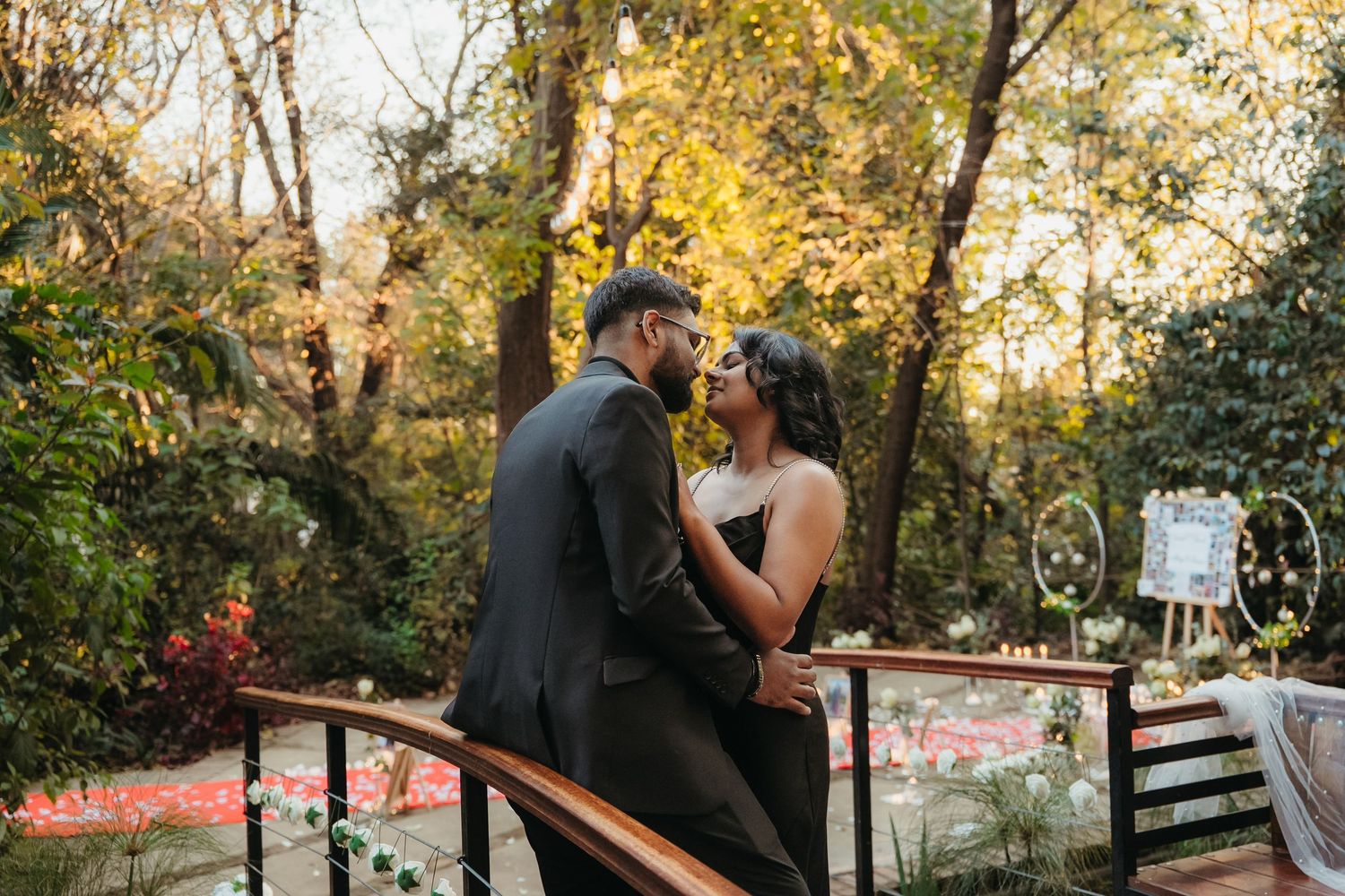 Couple sharing a romantic moment on a wooden deck surrounded by lush autumn trees at an outdoor wedding ceremony.