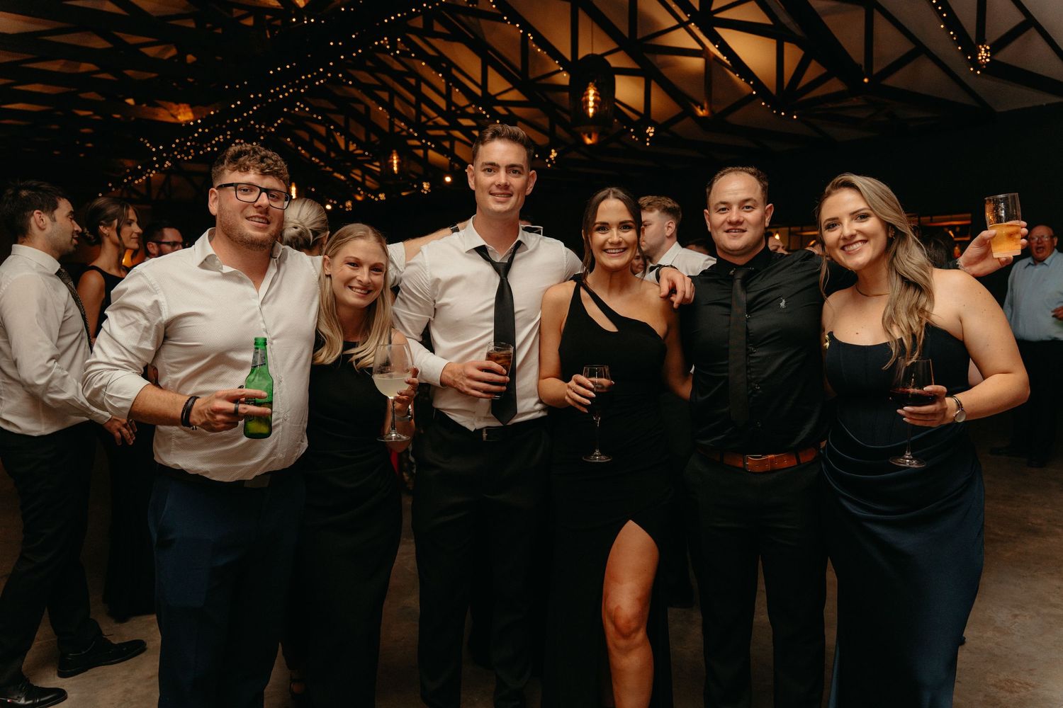 A group of people enjoying drinks and socializing at a dimly lit bar or party venue.
