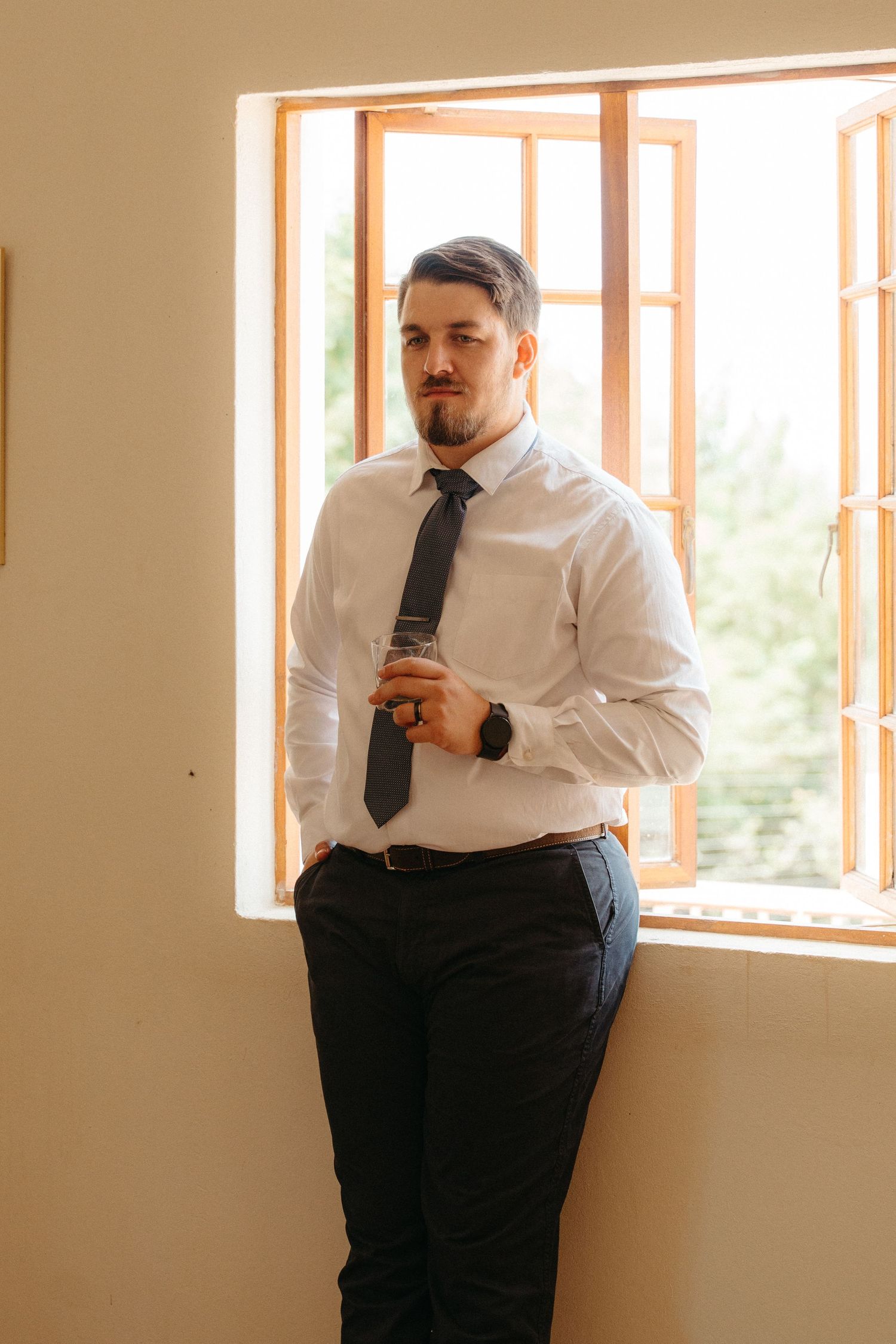 A person in business attire sits in a bright room with large windows, shown in a series of four connected photos.