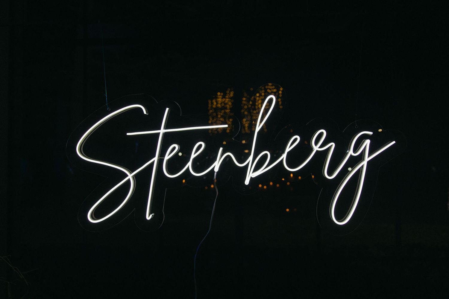 White neon text reading 'Steenberg' glows against a dark background with a small gold crown decoration above.