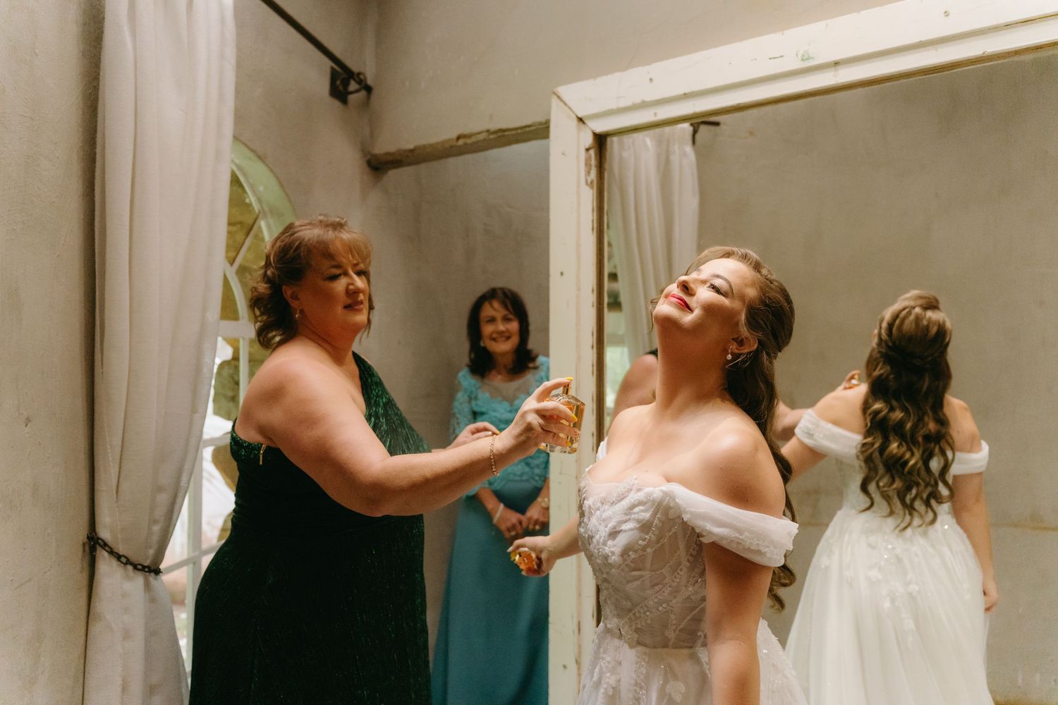 A joyful moment captured during wedding preparations as attendants help with the dress.