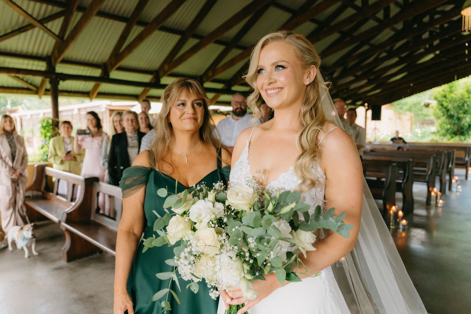 Wedding party celebrating under a covered outdoor venue with greenery and floral decorations.