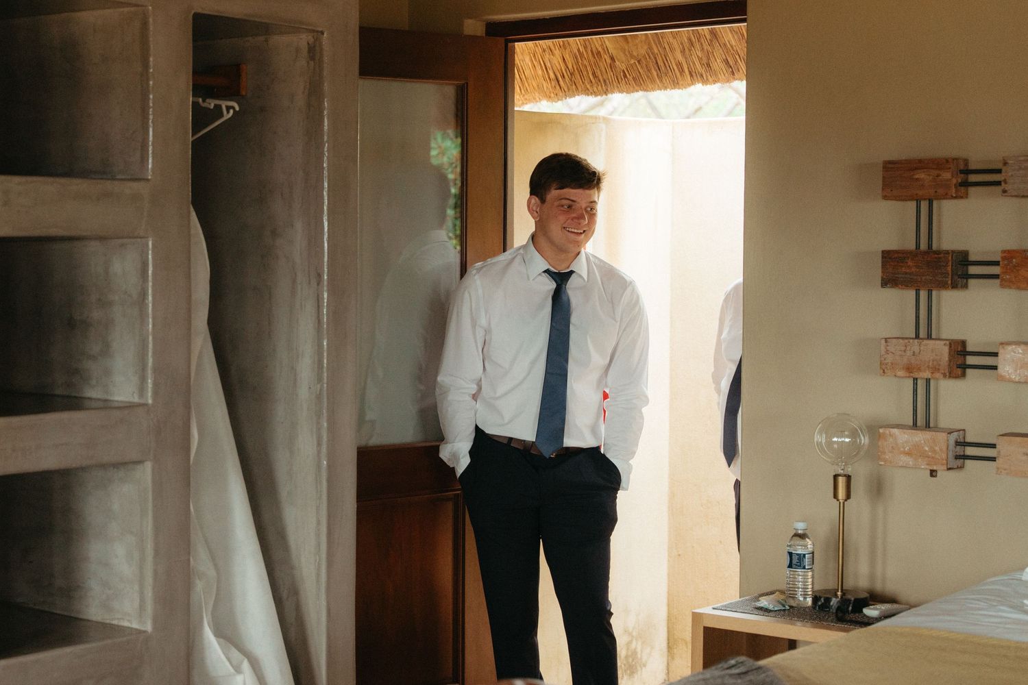 Wedding preparation scene in a sunlit room with formal attire visible.