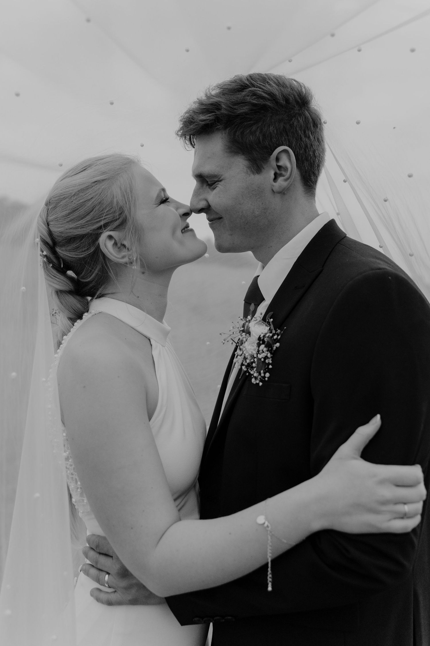 A series of romantic black and white wedding photos showing tender moments between a couple during their first kiss.
