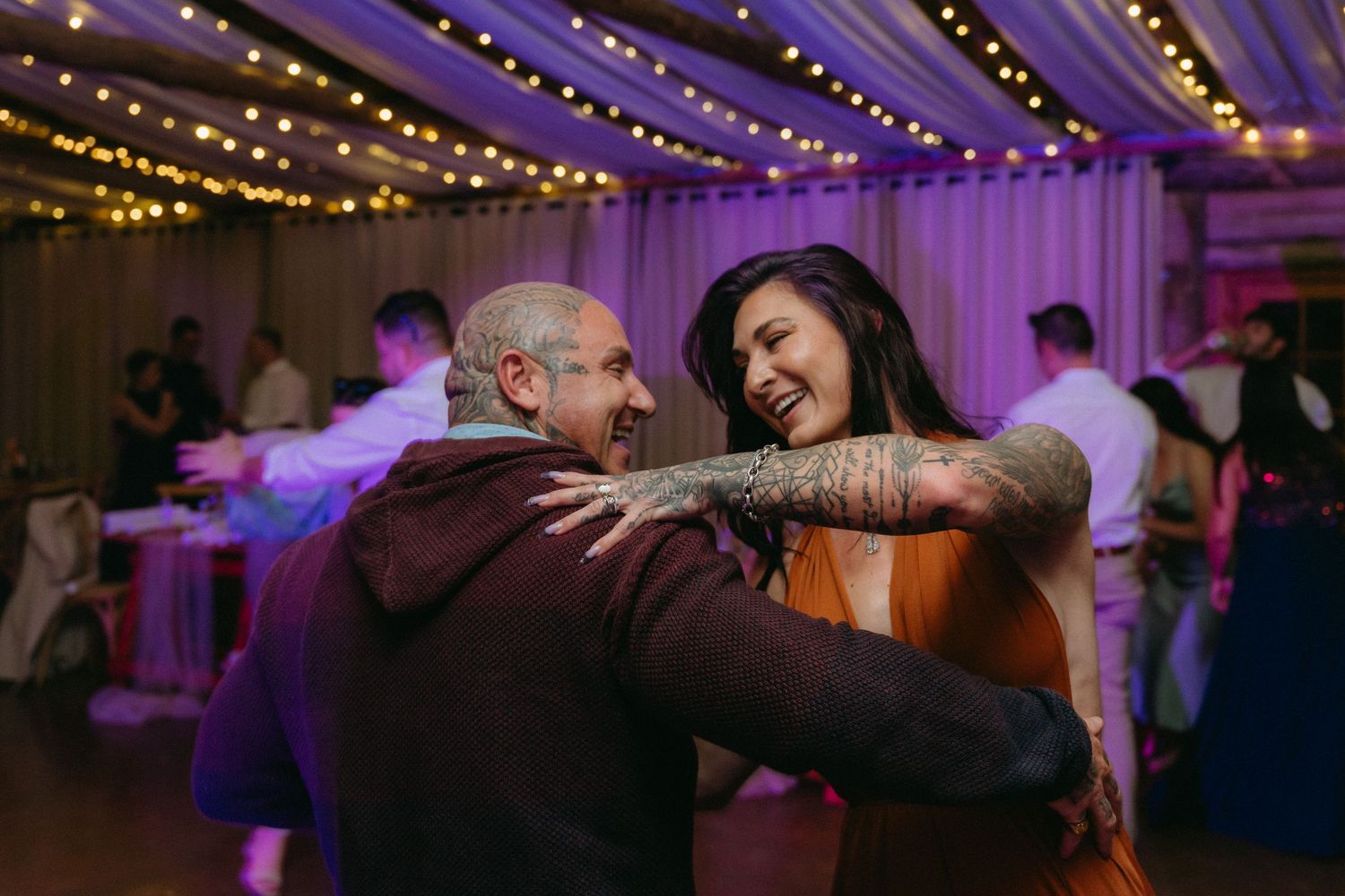 Wedding reception dance floor illuminated with purple and gold lighting effects.