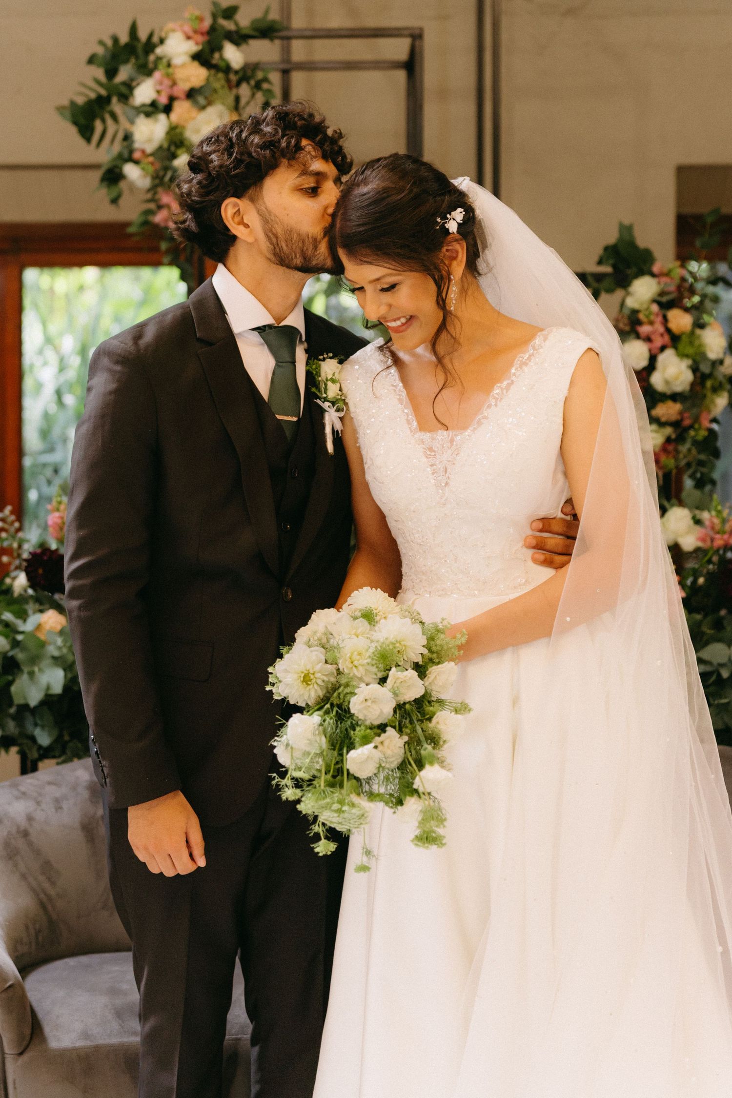 An elegant indoor wedding scene with romantic floral arrangements and tender moments between the couple.