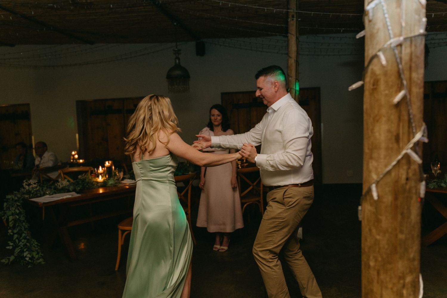 Wedding guests dance and celebrate on the dance floor at an indoor reception venue.