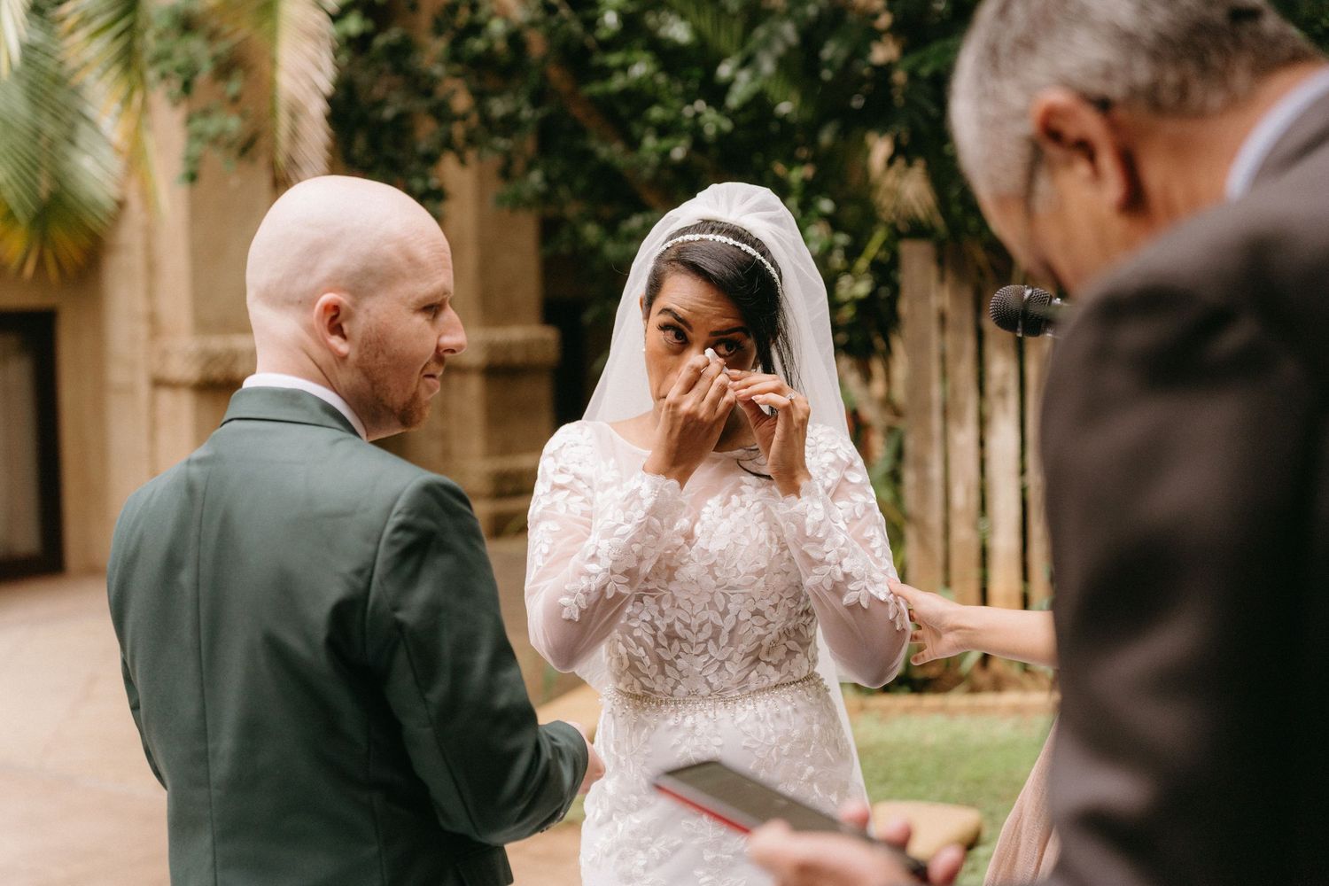 An emotional moment during an outdoor wedding ceremony as the bride wipes away tears while exchanging vows.
