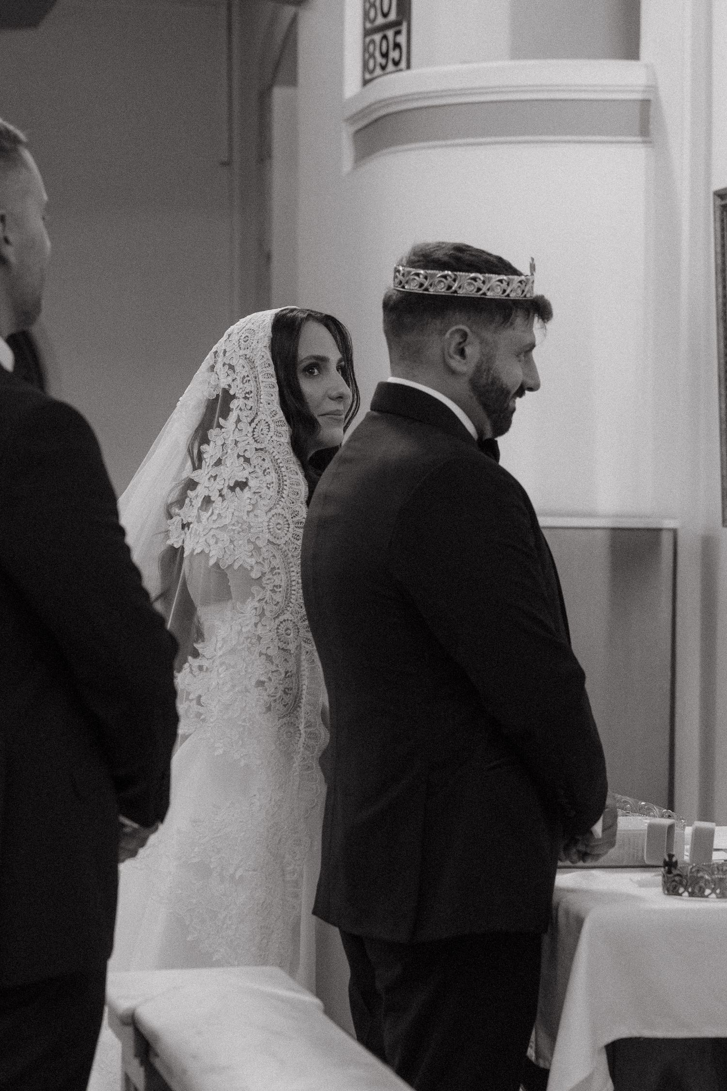 Black and white wedding photo of bride in lace veil and groom wearing crown during Rosebank Catholic Church ceremony.