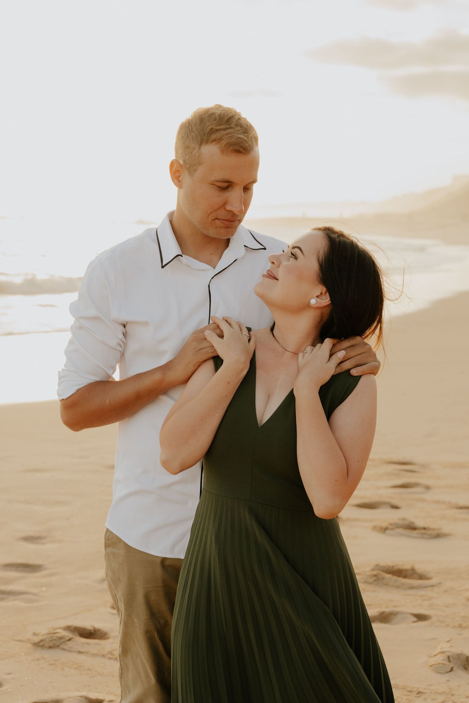 A romantic couple shares tender moments on a sandy beach at sunset in Mossel Bay, Western Cape