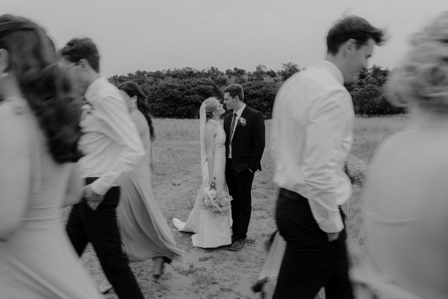 Wedding guests mingling outdoors in black and white photography.