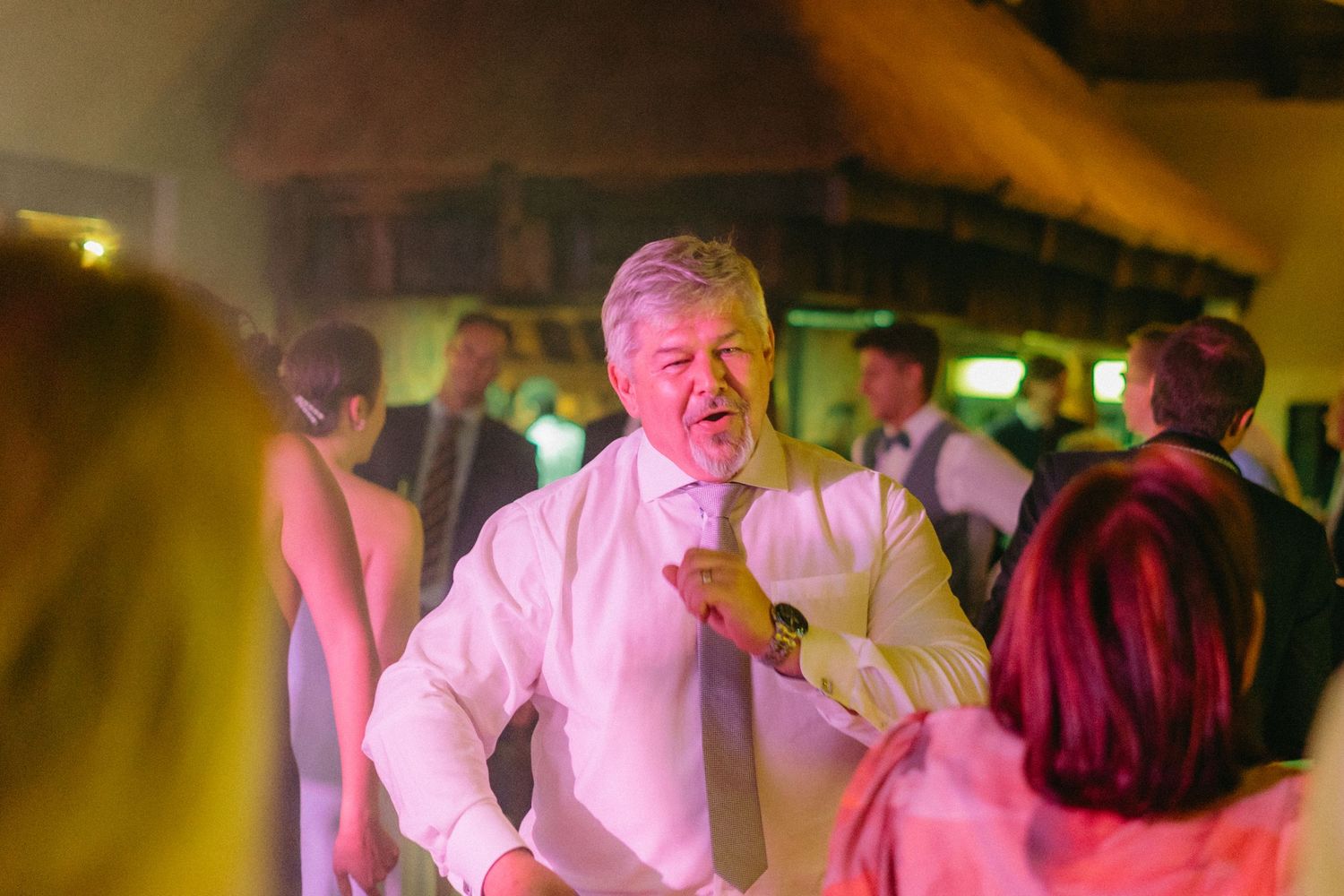 Wedding reception dance floor filled with guests under warm lighting.