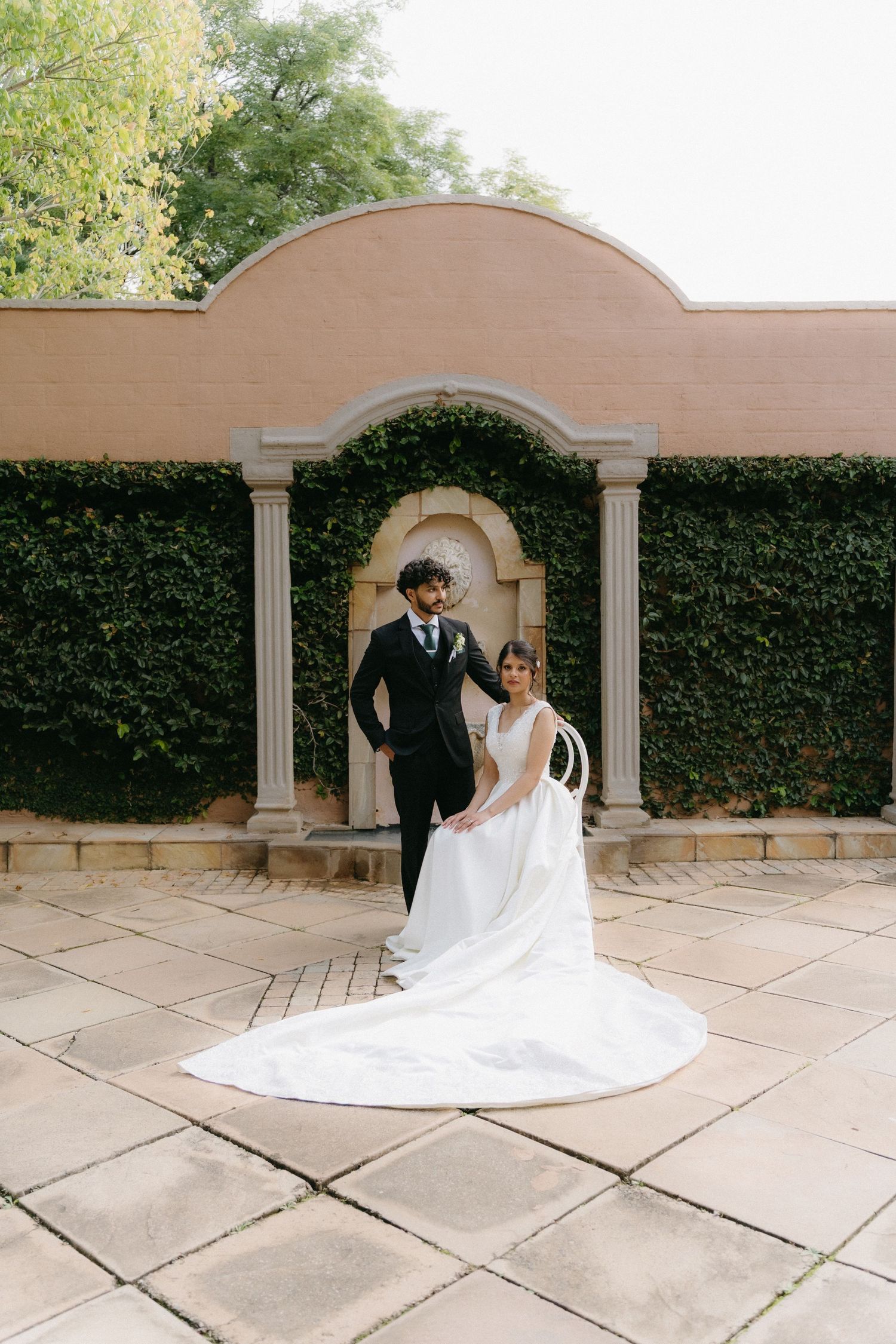 A dramatic wedding photo sequence showing a flowing white dress train against stone archways and columns.