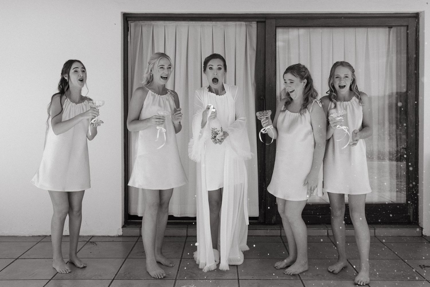 A black and white collage of young children in white dresses standing in a row against a wall.