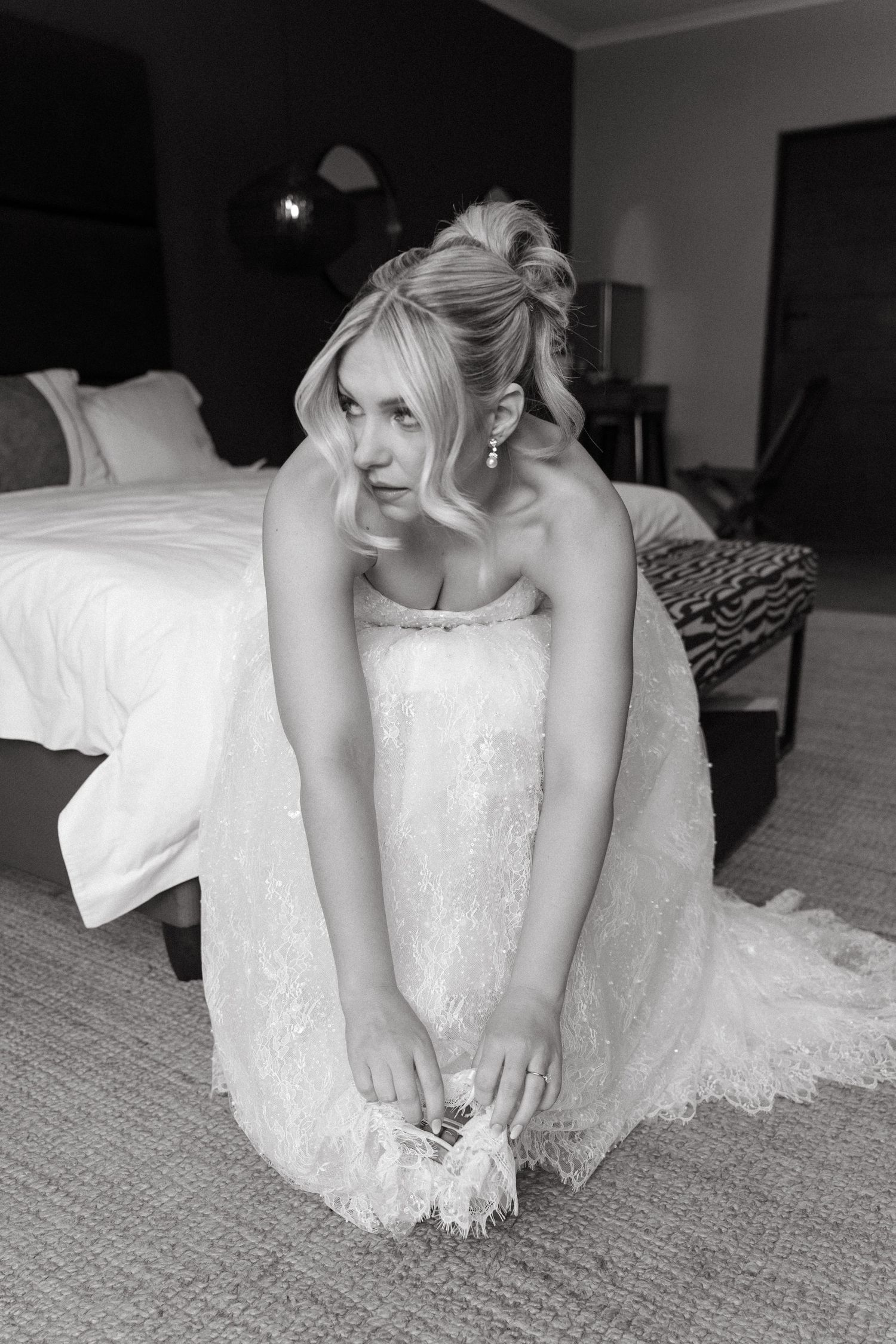 A black and white photo series showing close-up details of a white lace wedding dress against carpet flooring.