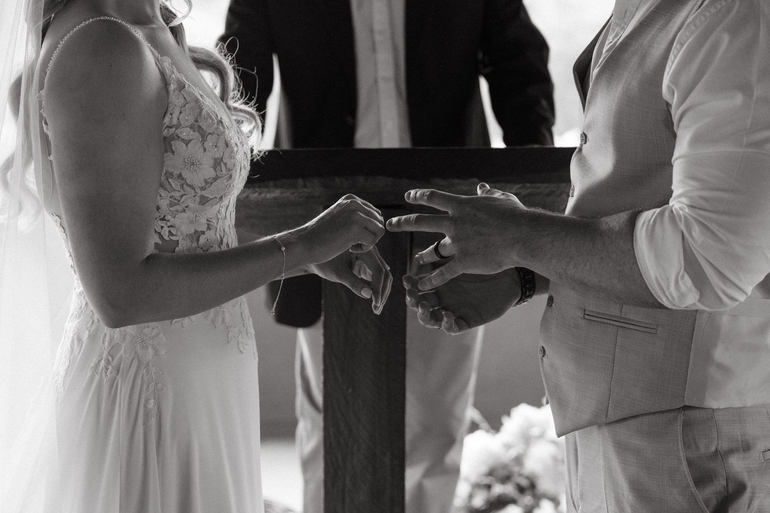 Wedding ceremony candid moments in black and white under wooden shelter.