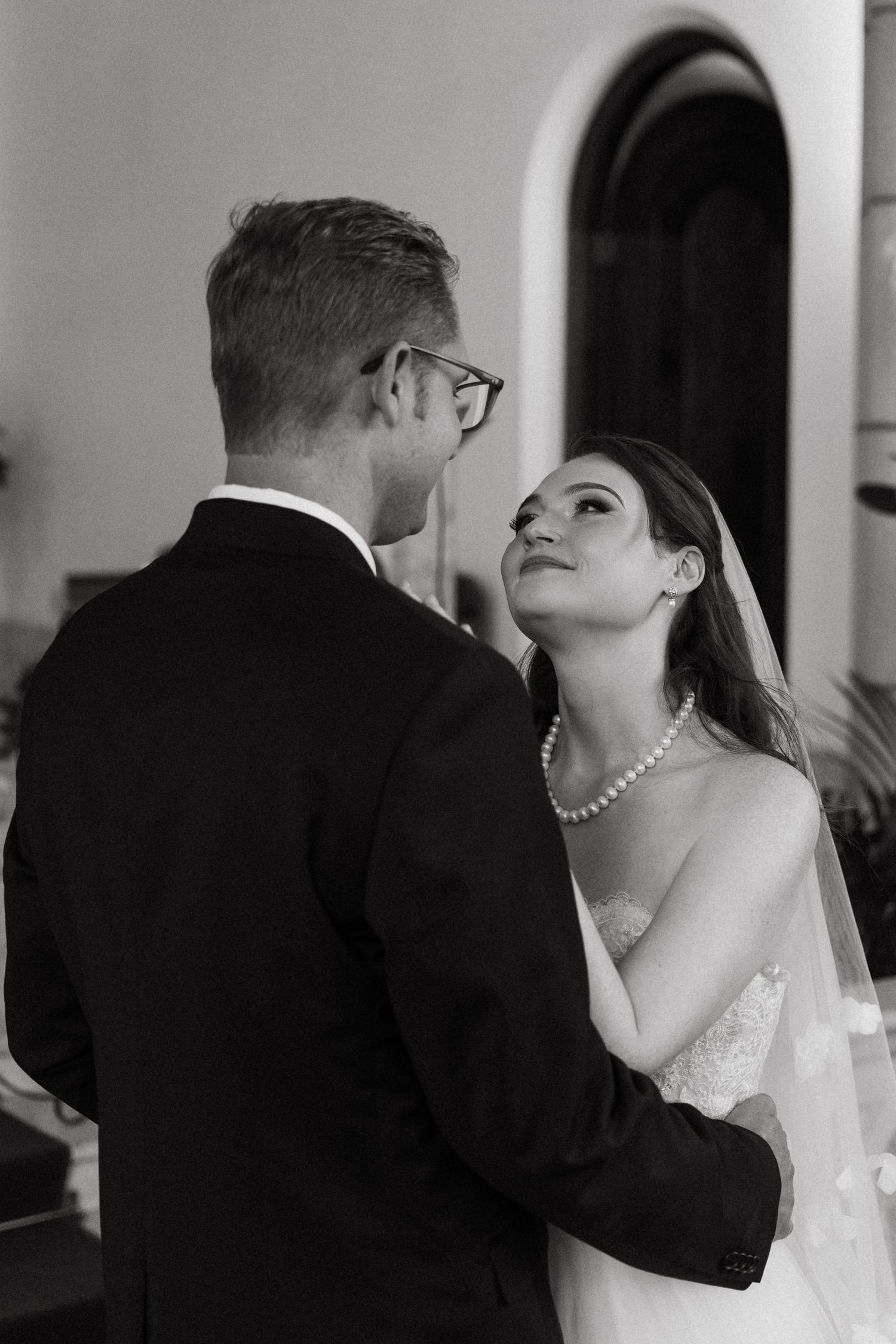 A black and white photo of a bride gazing up at her groom.