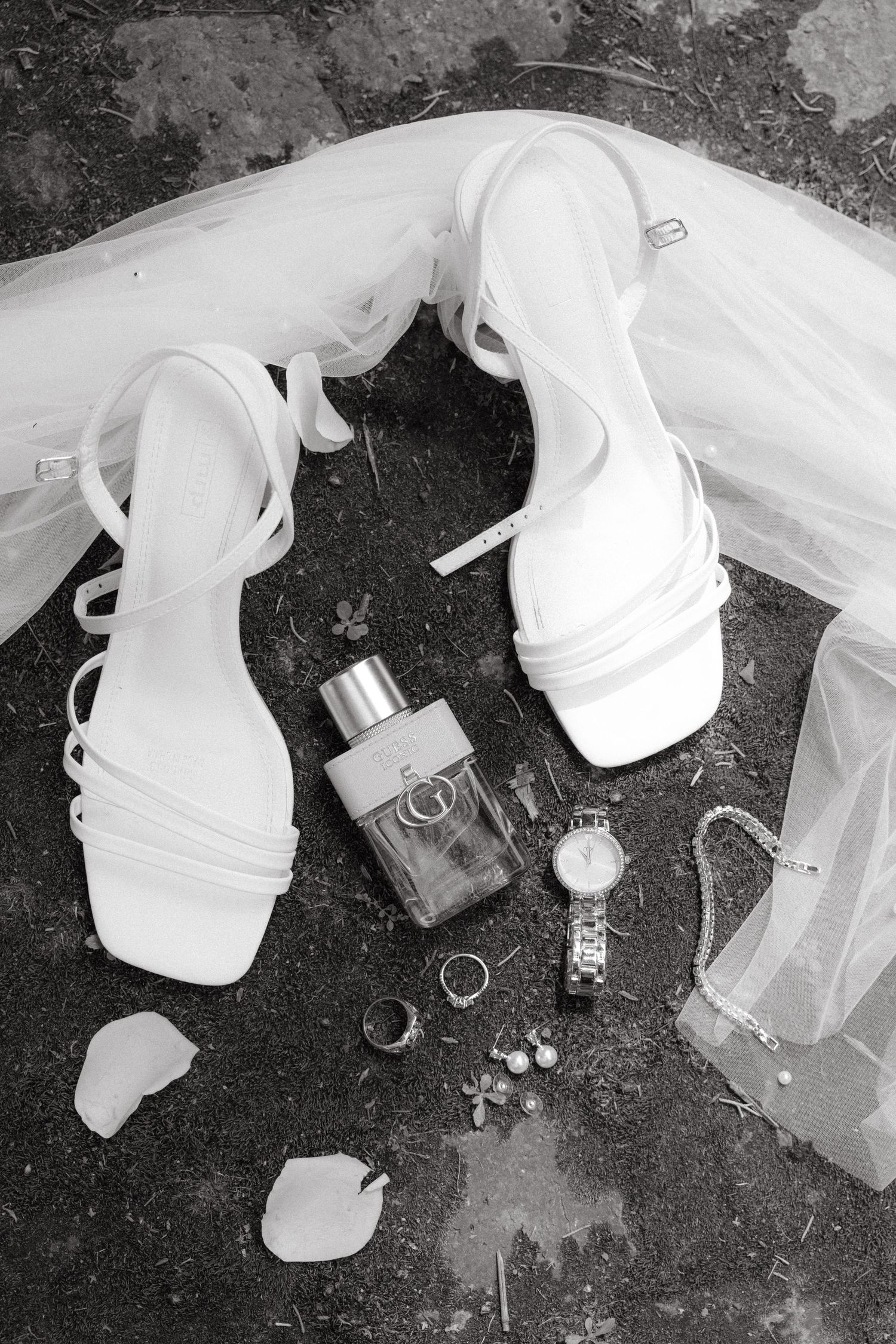 Black and white detail shots of wedding dress and accessories laid out on dark surface.