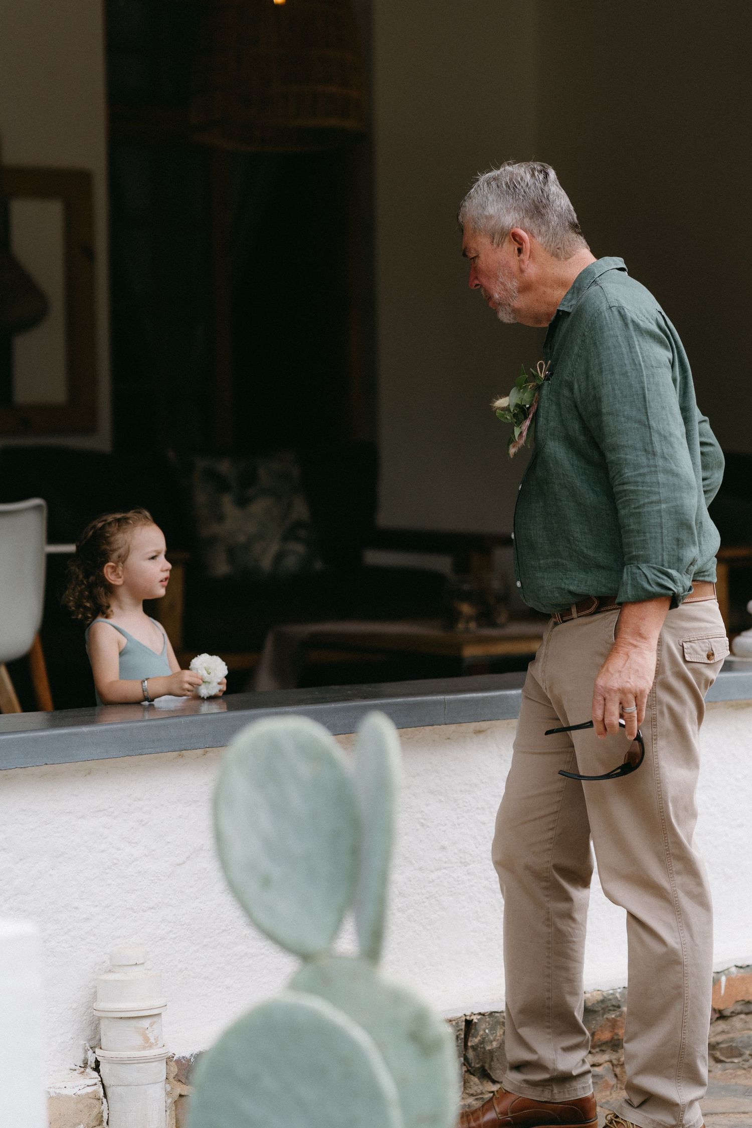 A candid outdoor scene with a child and senior person interacting near a stone patio.
