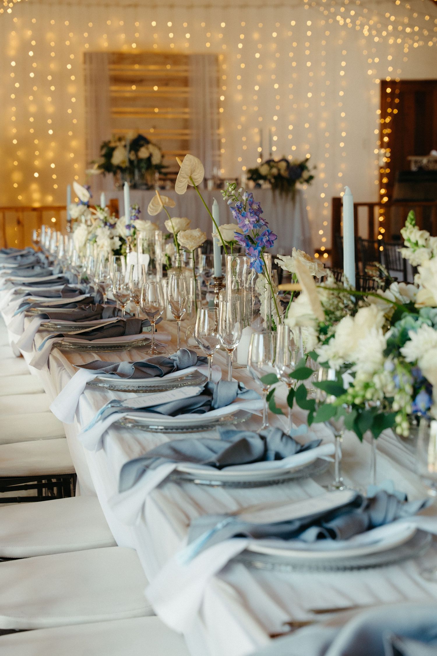 Elegant Steynshoop Valley Lodgwedding reception table with blue linen napkins, crystal glasses, white floral centerpieces, and fairy lights.