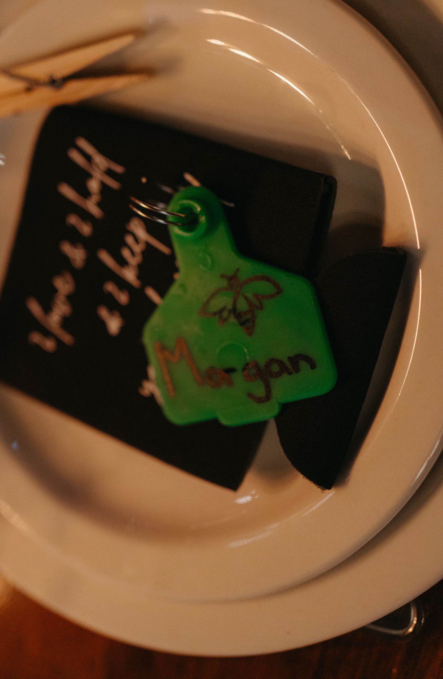 Close-up of a green-colored wedding place card on a white plate.