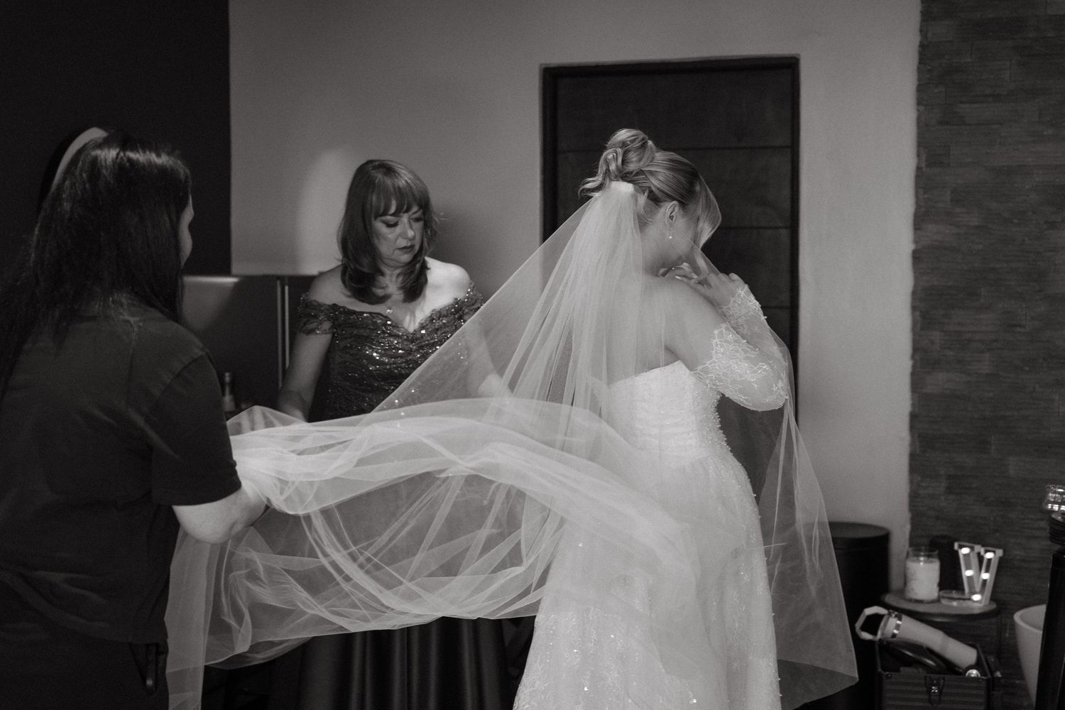 A bride's veil catches the light as it floats gracefully in an indoor setting.