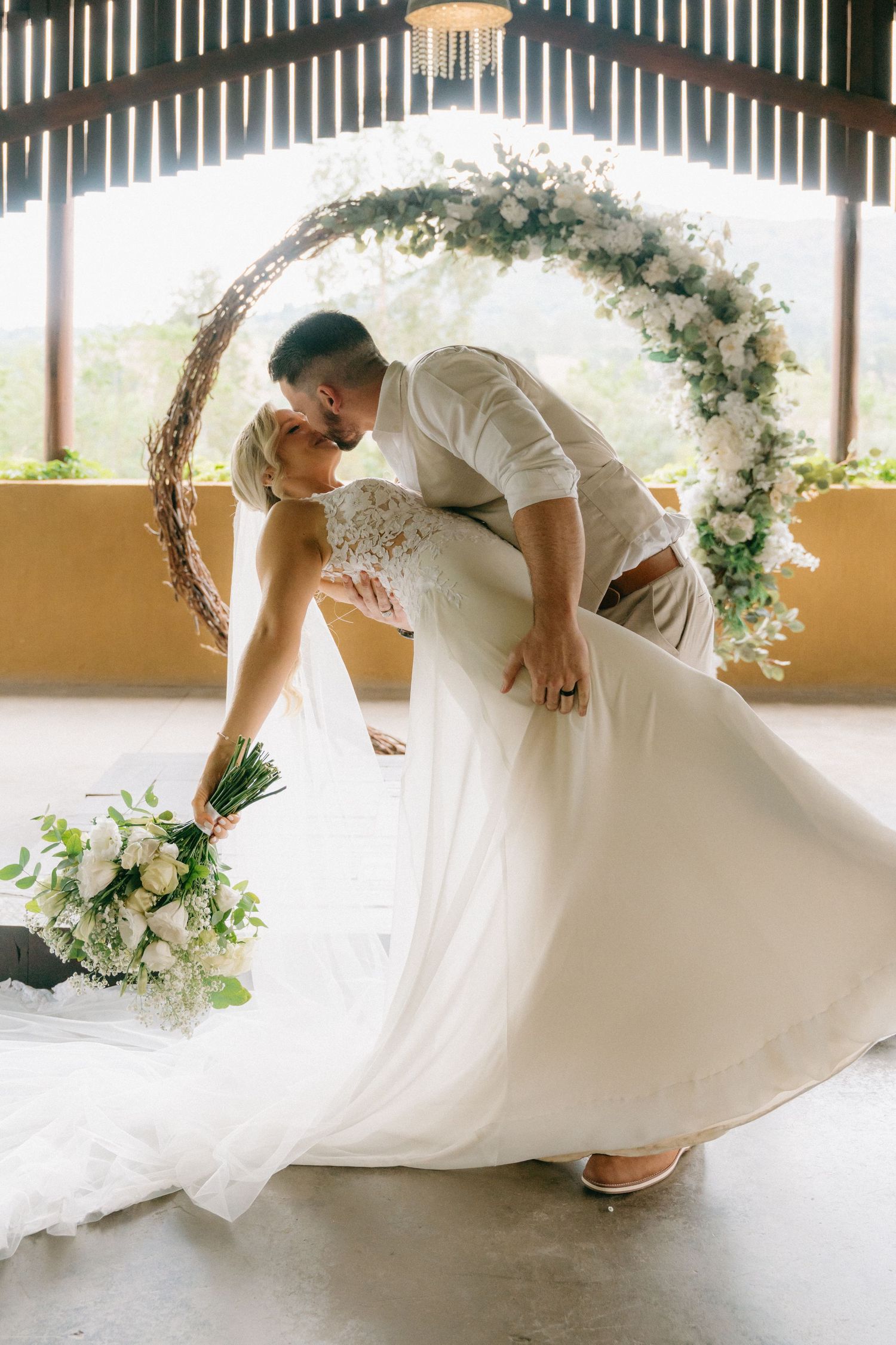 A flowing white wedding dress twirls gracefully under a decorated archway.