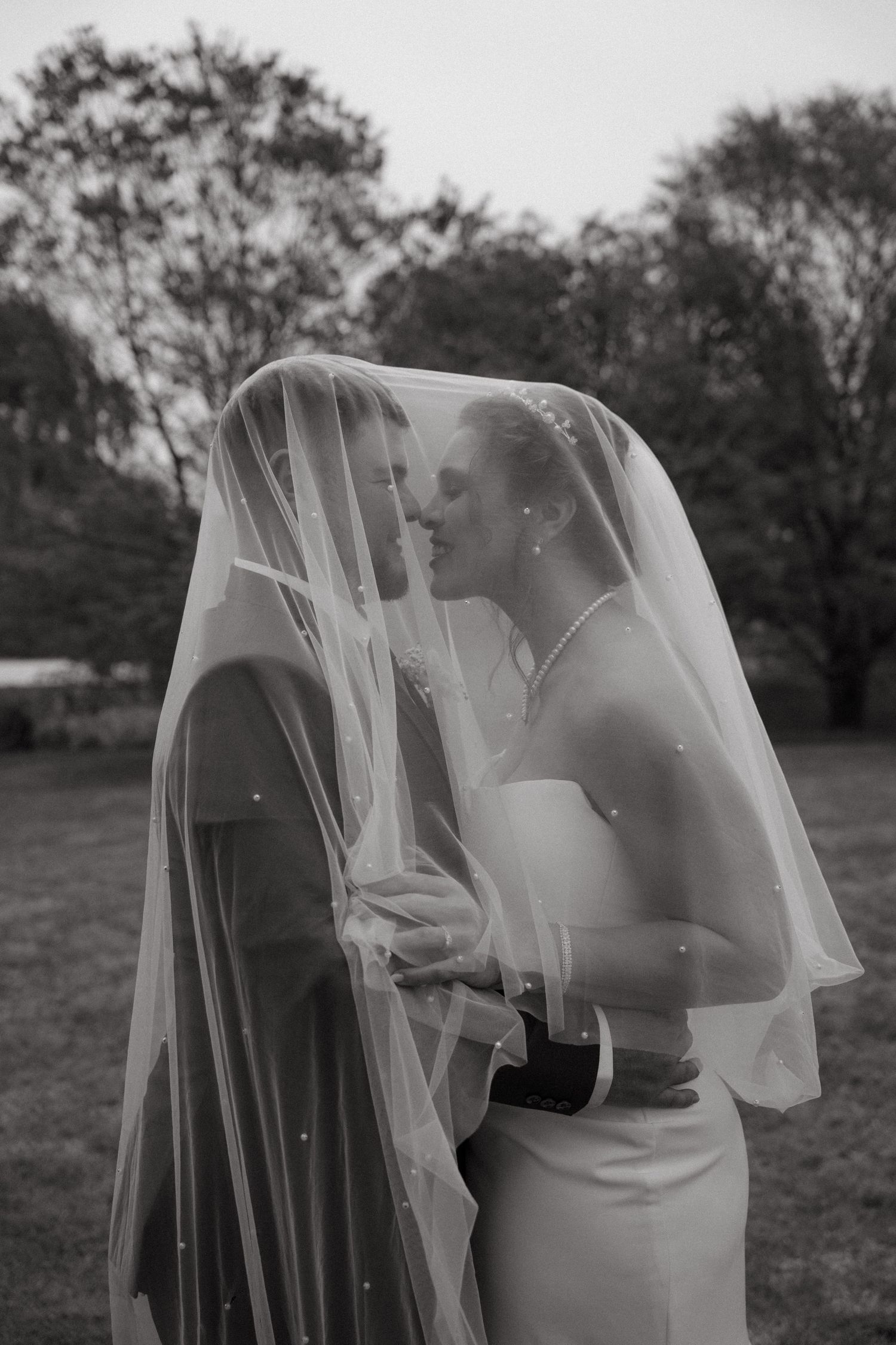 A romantic black and white wedding photo series showing a couple sharing intimate moments under a delicate veil.