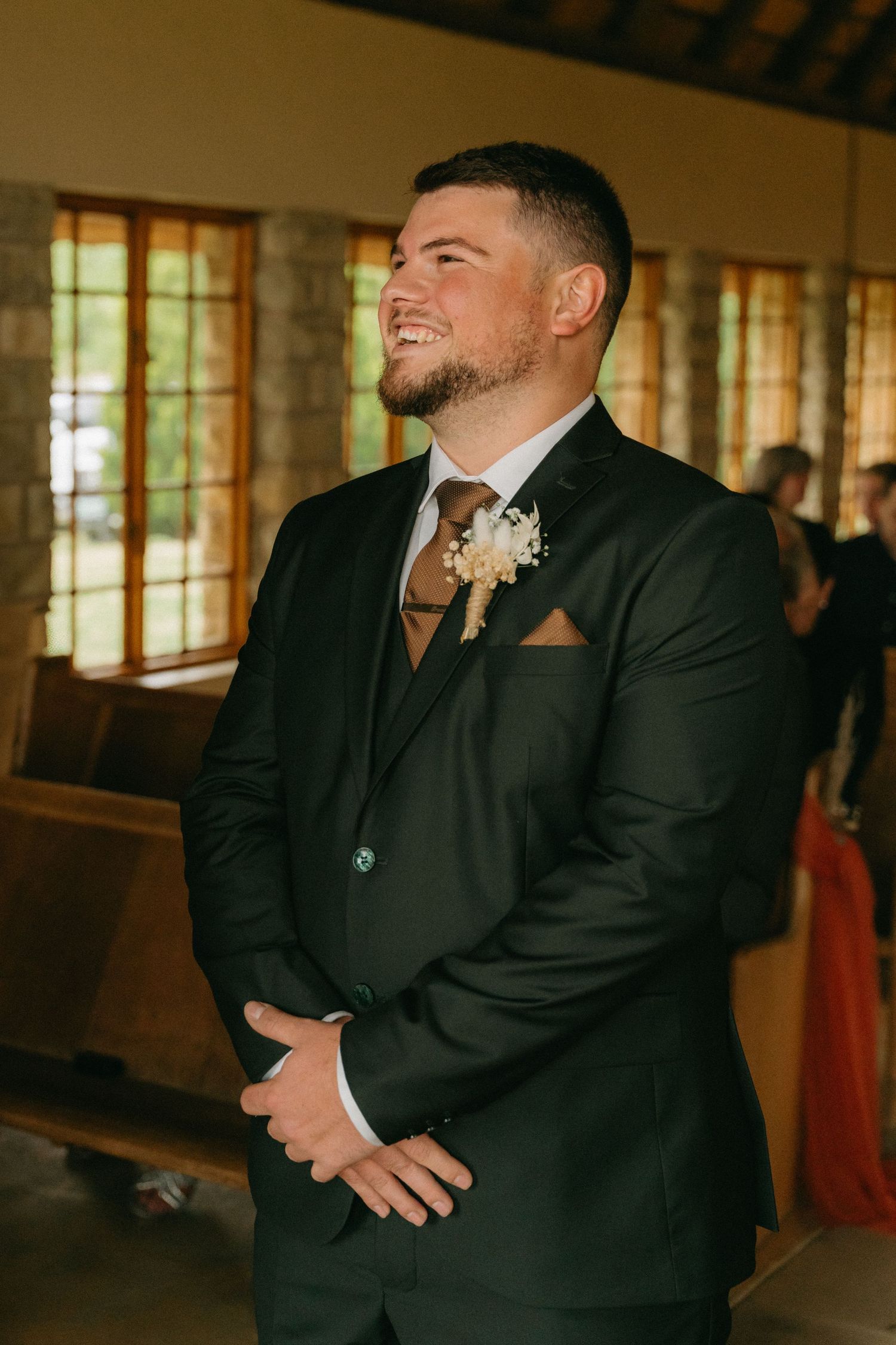 Groomsmen in black suits share reactions during an emotional wedding ceremony moment.