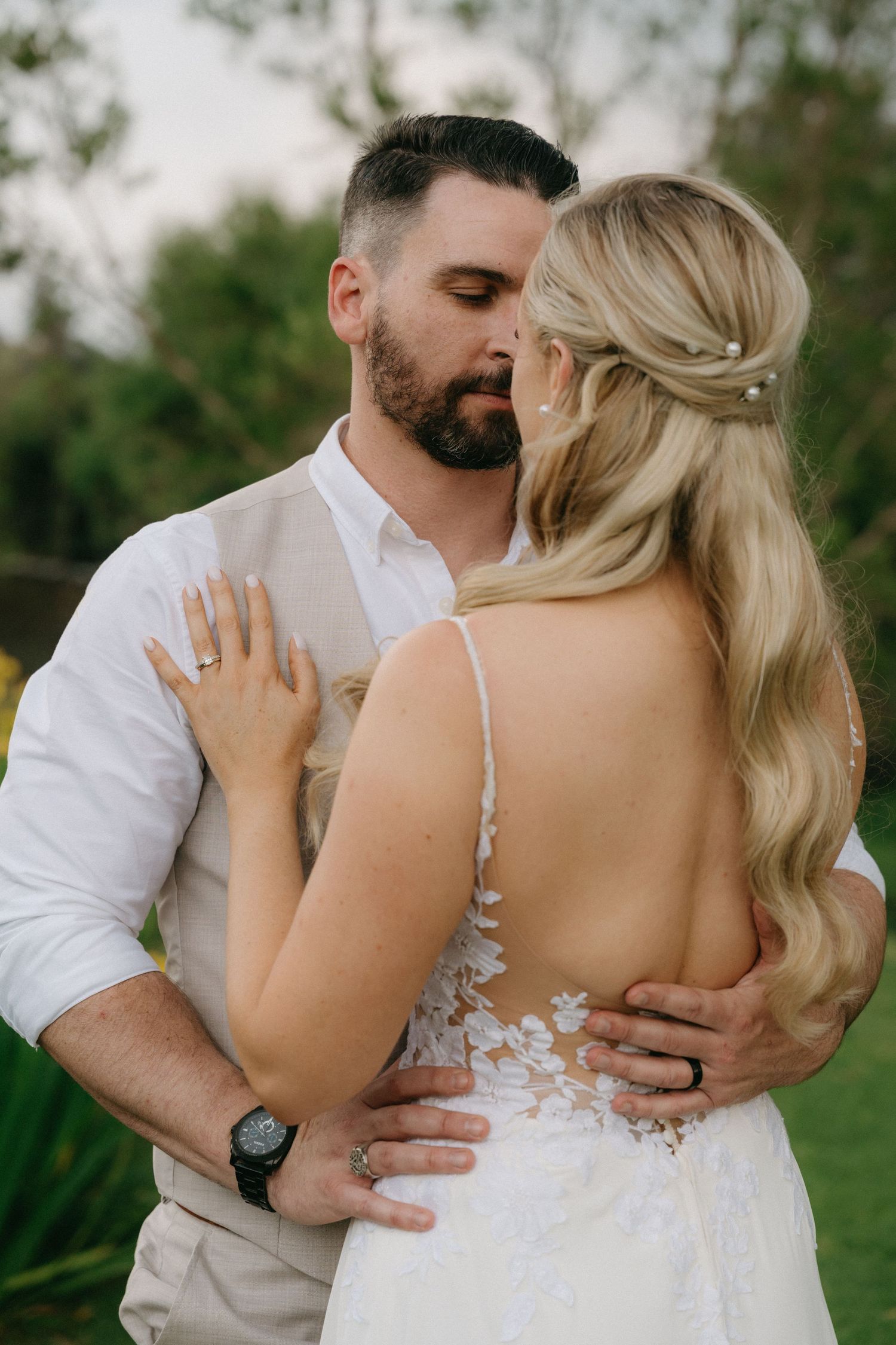 A romantic wedding portrait showing a couple embracing in an outdoor garden setting.