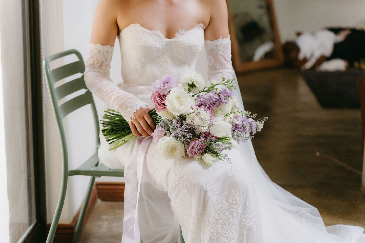 Close-up of bride holding delicate purple and white floral bouquet.