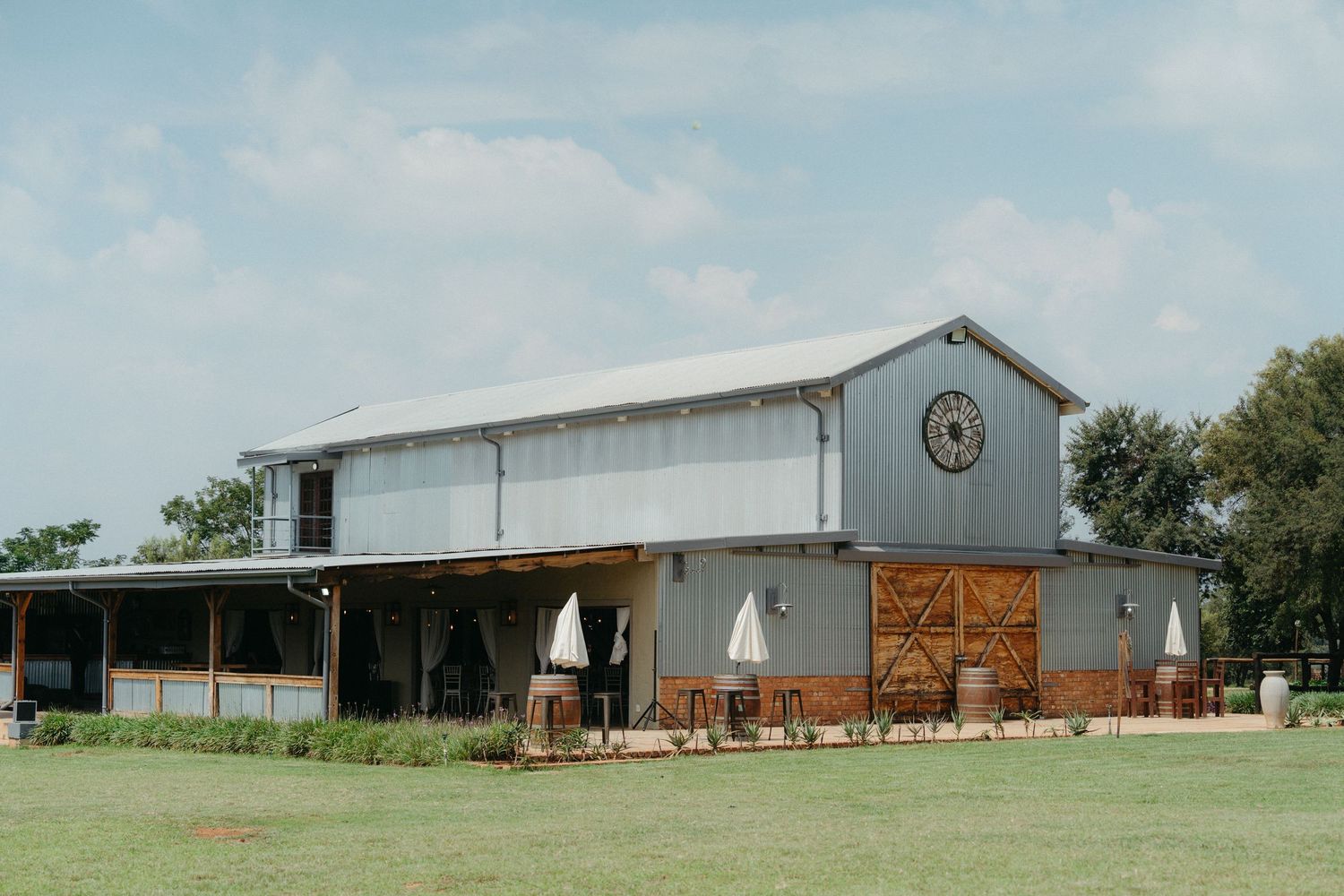 Modern farmhouse-style barn venue with metal siding and wooden accents in a pastoral setting.