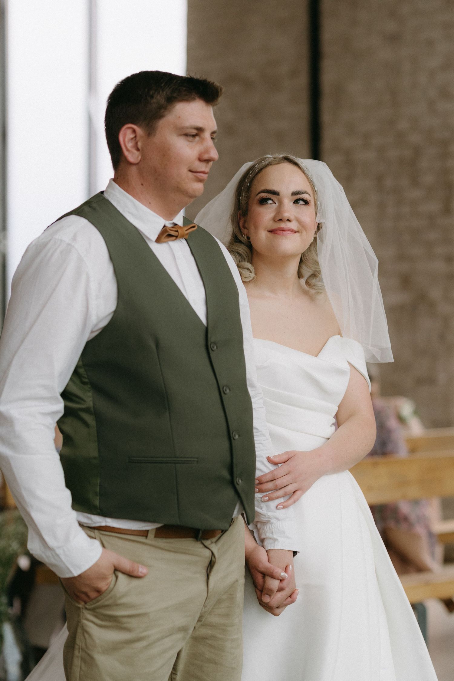 A tender wedding portrait of a couple in rustic attire with the bride wearing a classic white gown and veil.