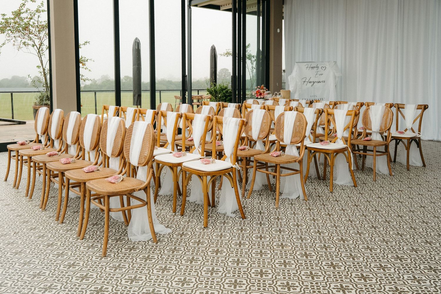 Elegant wedding ceremony setup with wooden cross-back chairs arranged in rows on patterned carpet in a modern Garden Route Wedding venue.