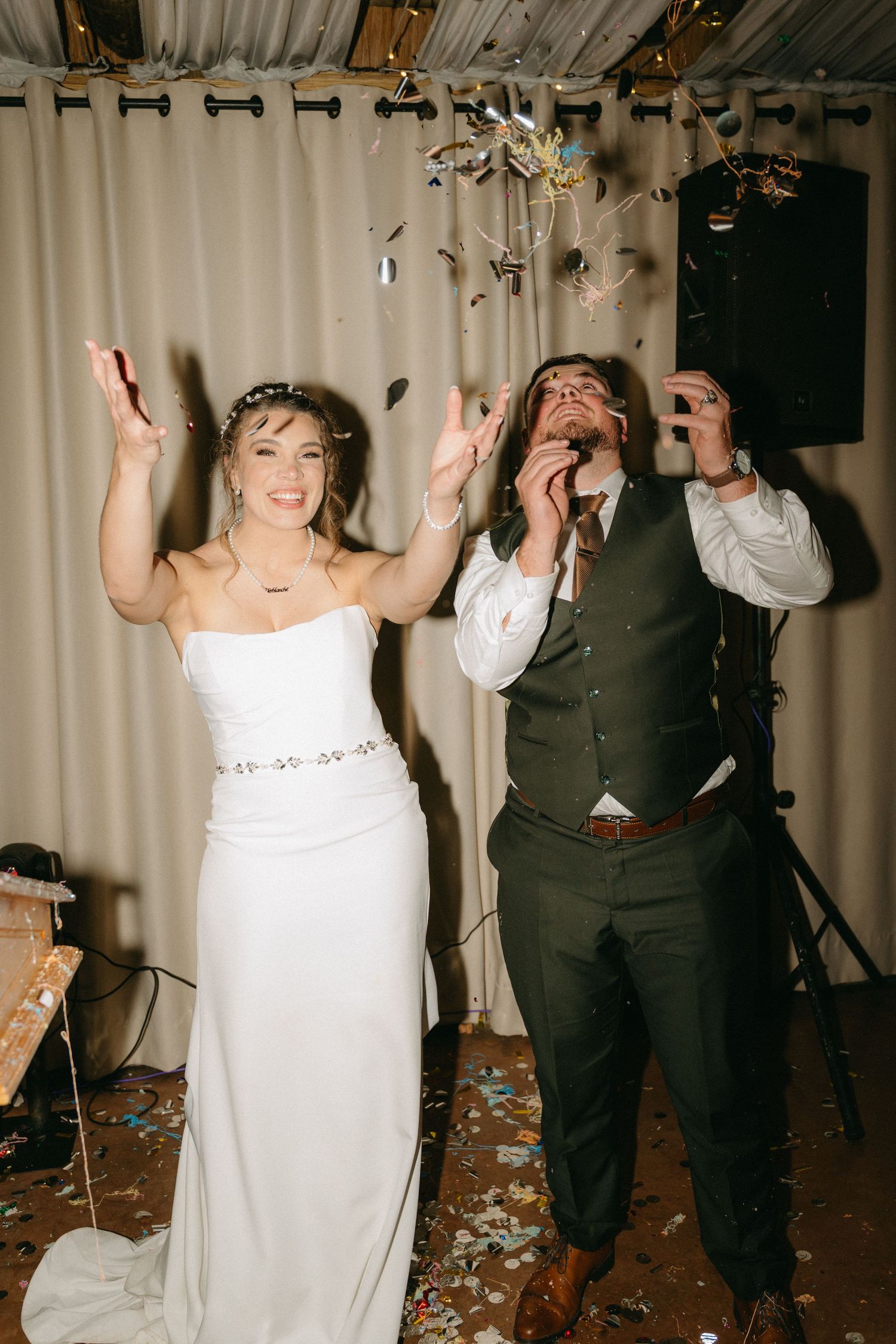 Wedding guests dancing and raising hands in celebration during reception party.