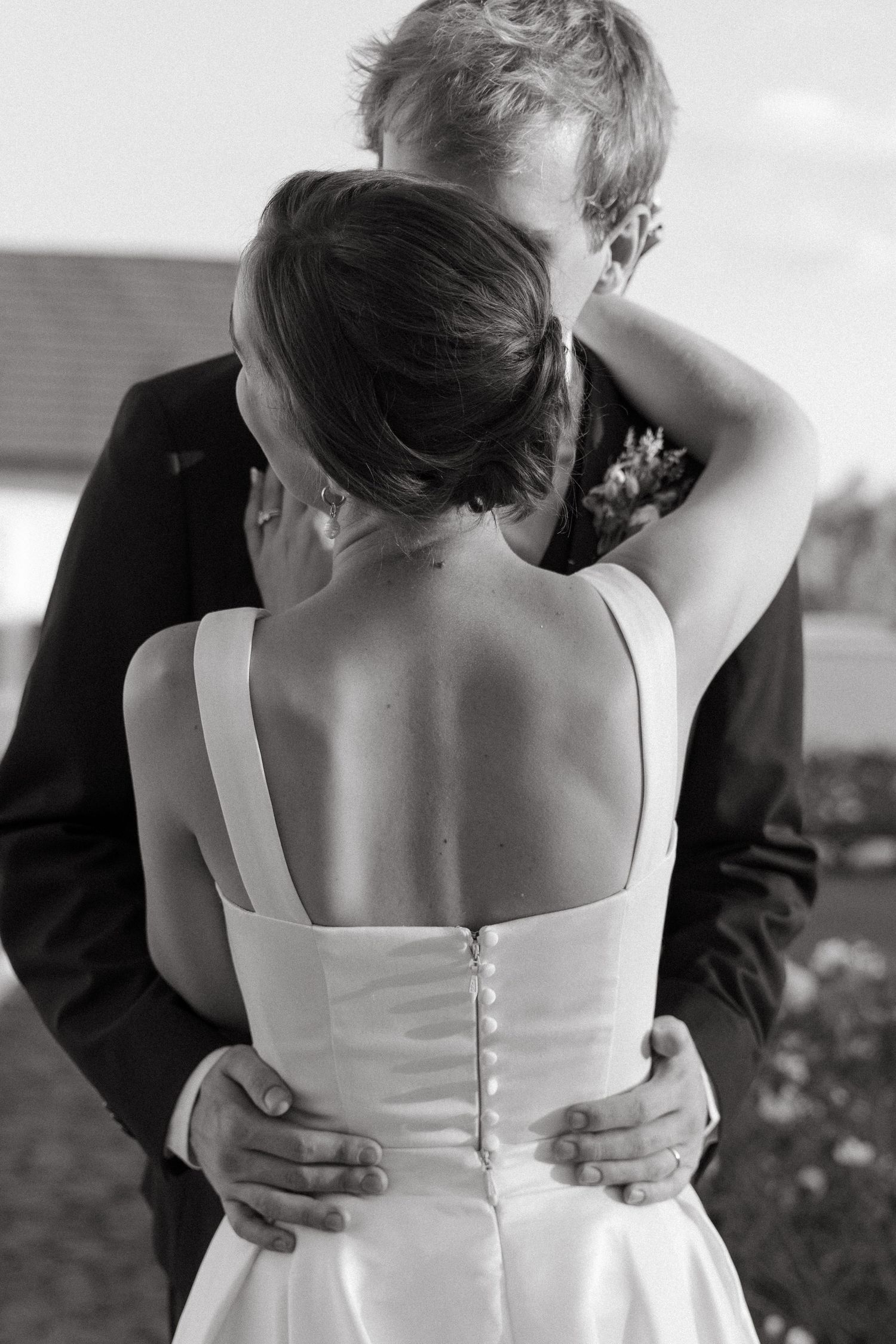 A romantic black and white photo series showing close-up views of a couple embracing, focusing on their backs and shoulders.