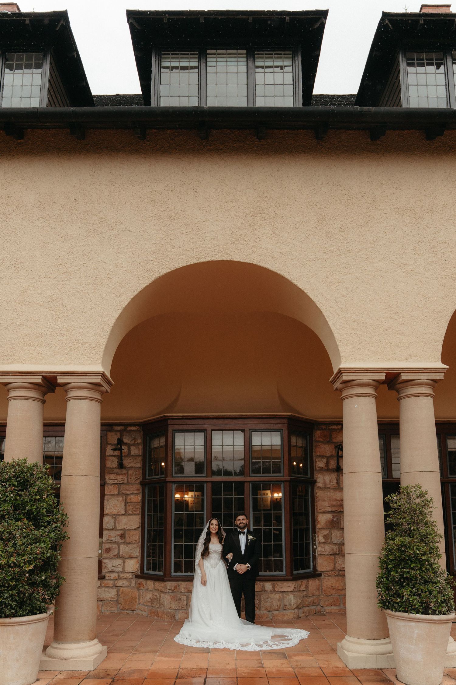 Bride and groom posing under elegant arched colonnade of historic Johannesburg home, Glenshiel