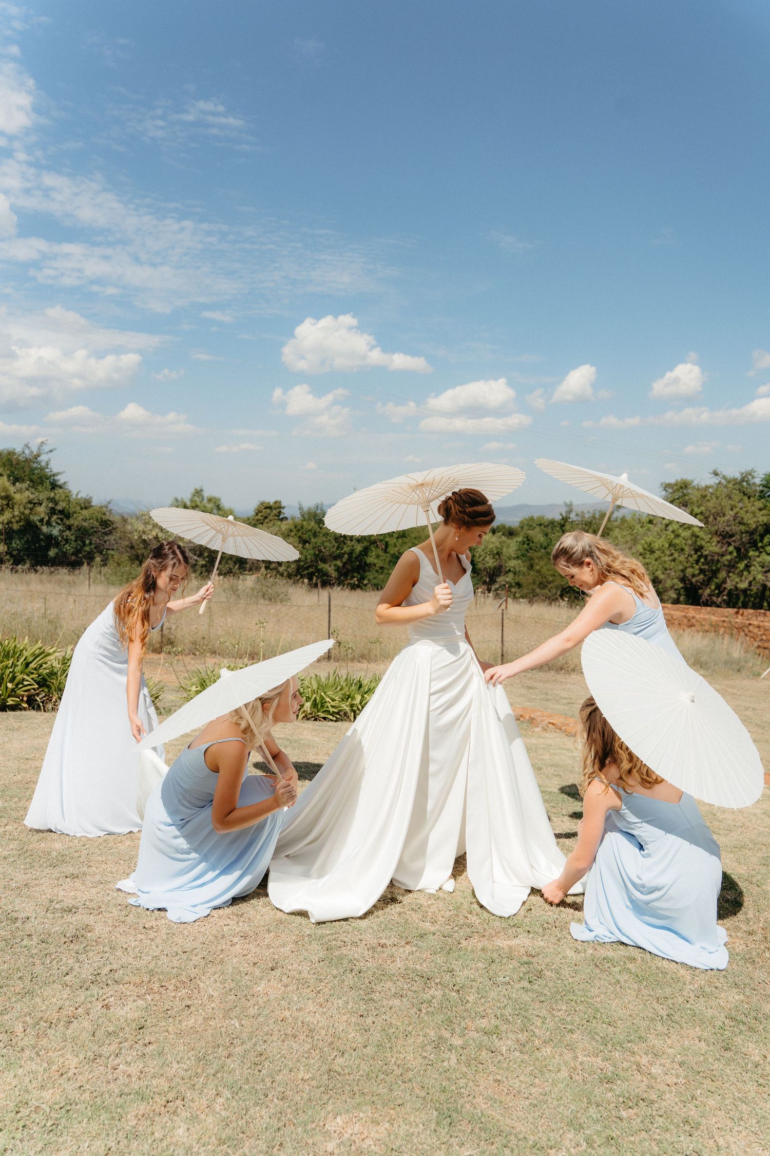 A sequence of flowing white fabric movements against a natural outdoor landscape on a sunny day.