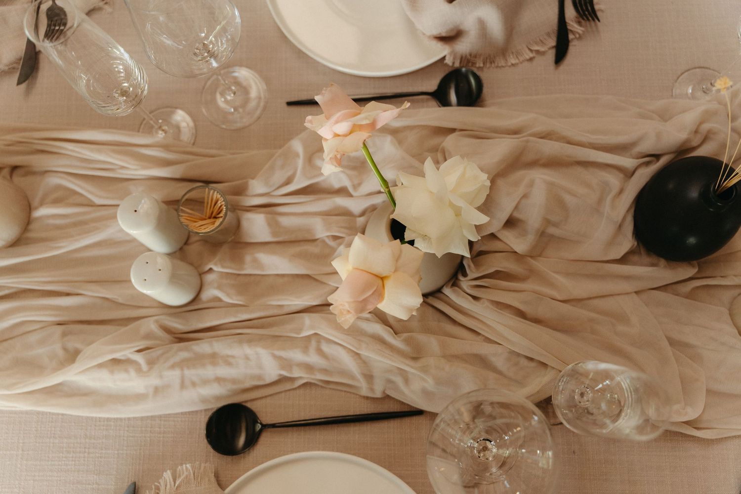 Elegant table setting with white flowers, crystal glasses, and blush pink linens creating a romantic atmosphere.