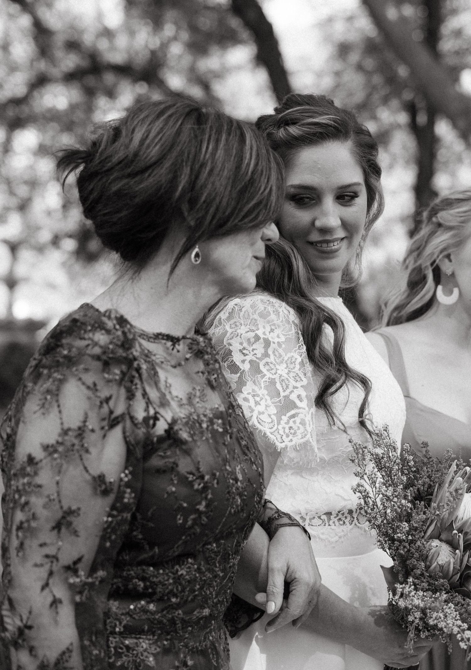 Black and white portrait of two people sharing an intimate moment with wildflower bouquets.