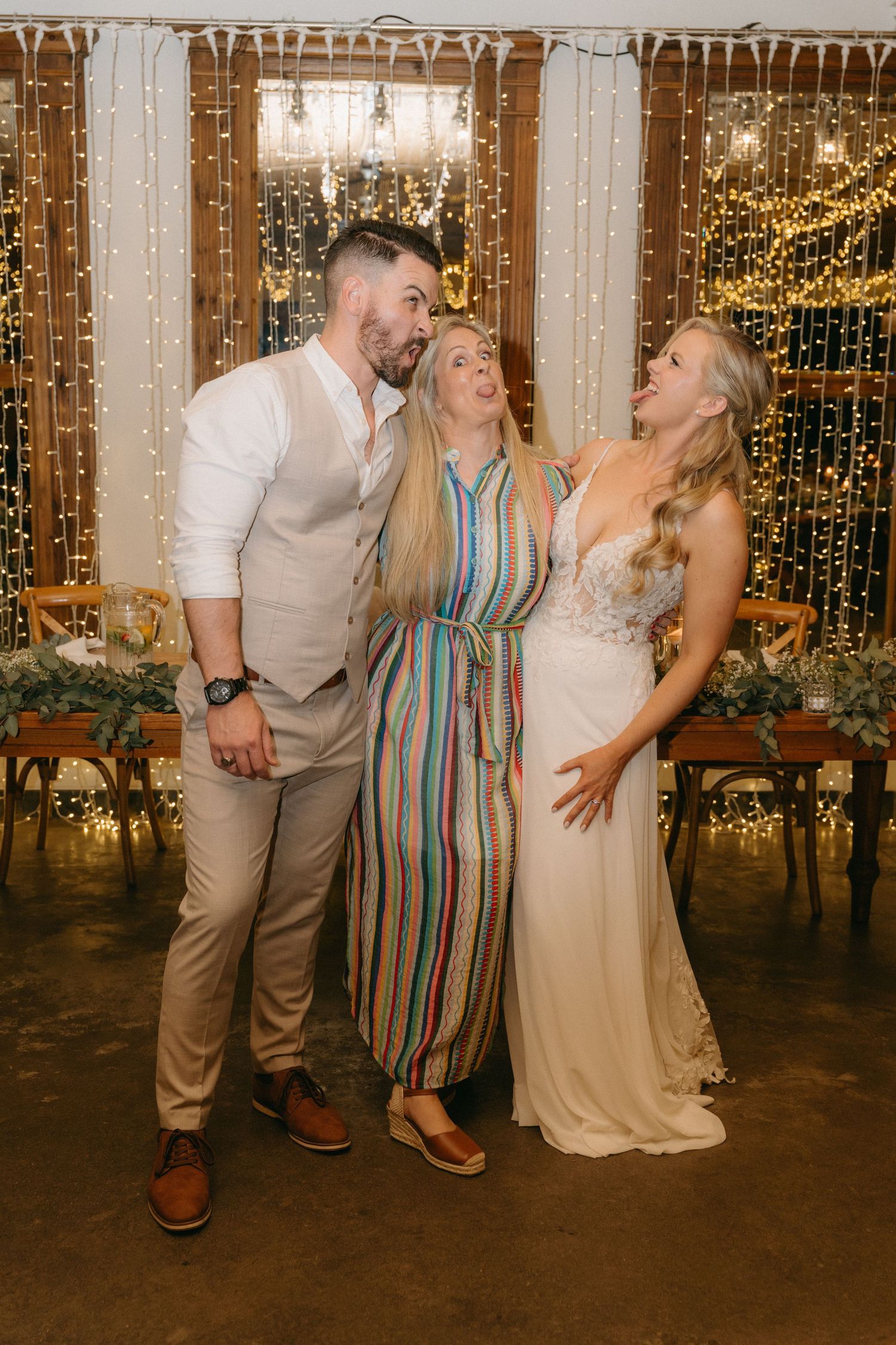 Wedding party laughs together in front of a sparkly backdrop at an evening reception.