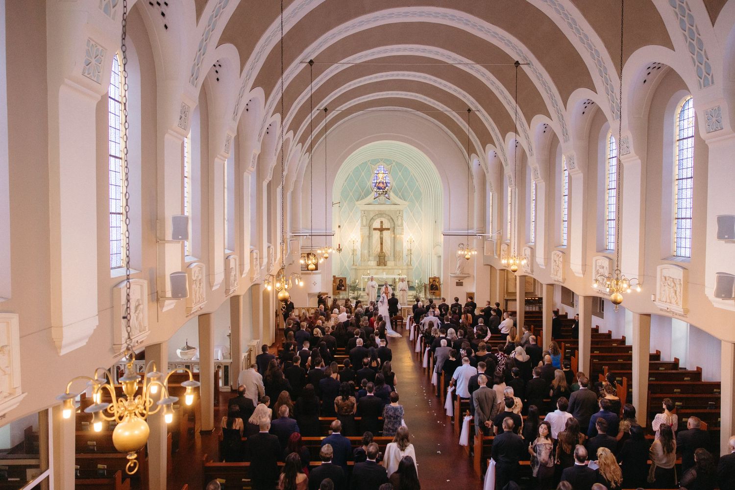 Aerial view of a wedding ceremony in Rosebank Catholic Church, filled with guests seated in wooden pews.