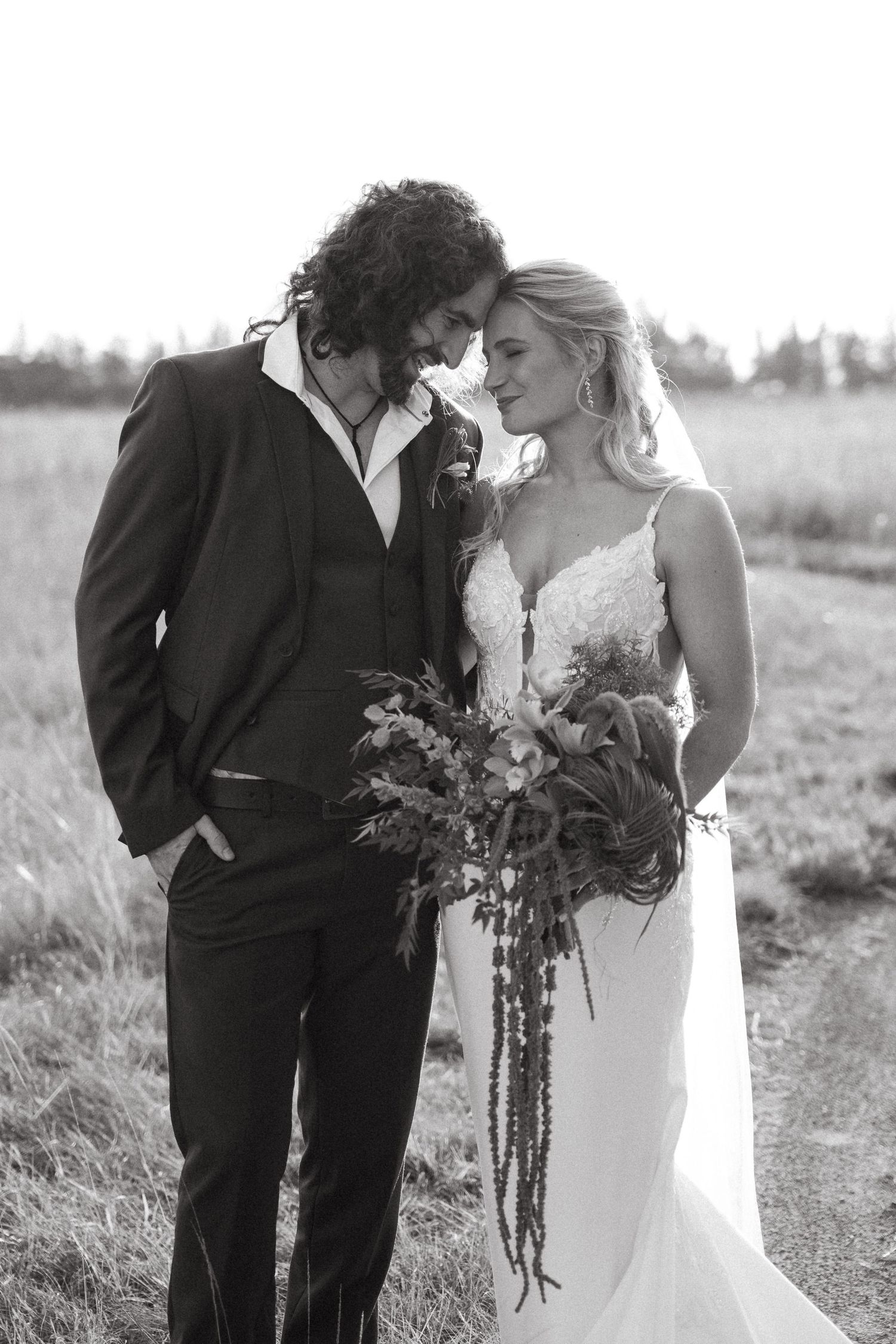 Black and white photo of a bride and groom sharing an intimate moment outdoors, bride holding a cascading bouquet.