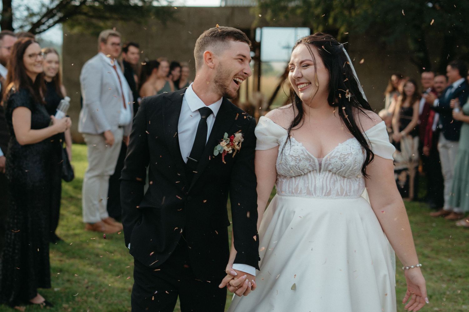 A celebratory moment at an outdoor wedding as confetti falls around the couple.