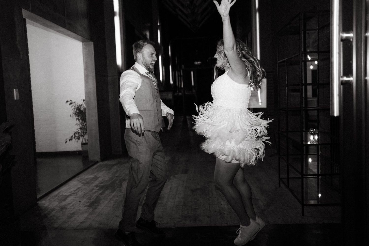 Couple dances energetically in black and white, with the bride wearing a flowy dress.
