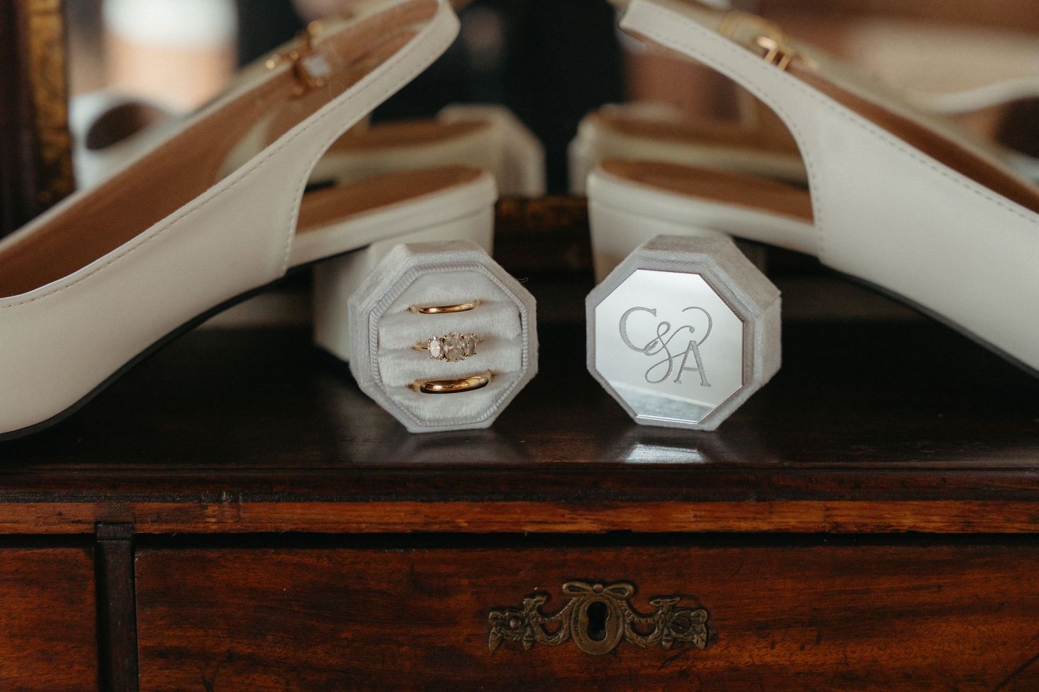 Close-up view of silver and gold wedding rings resting on a dark wooden surface.