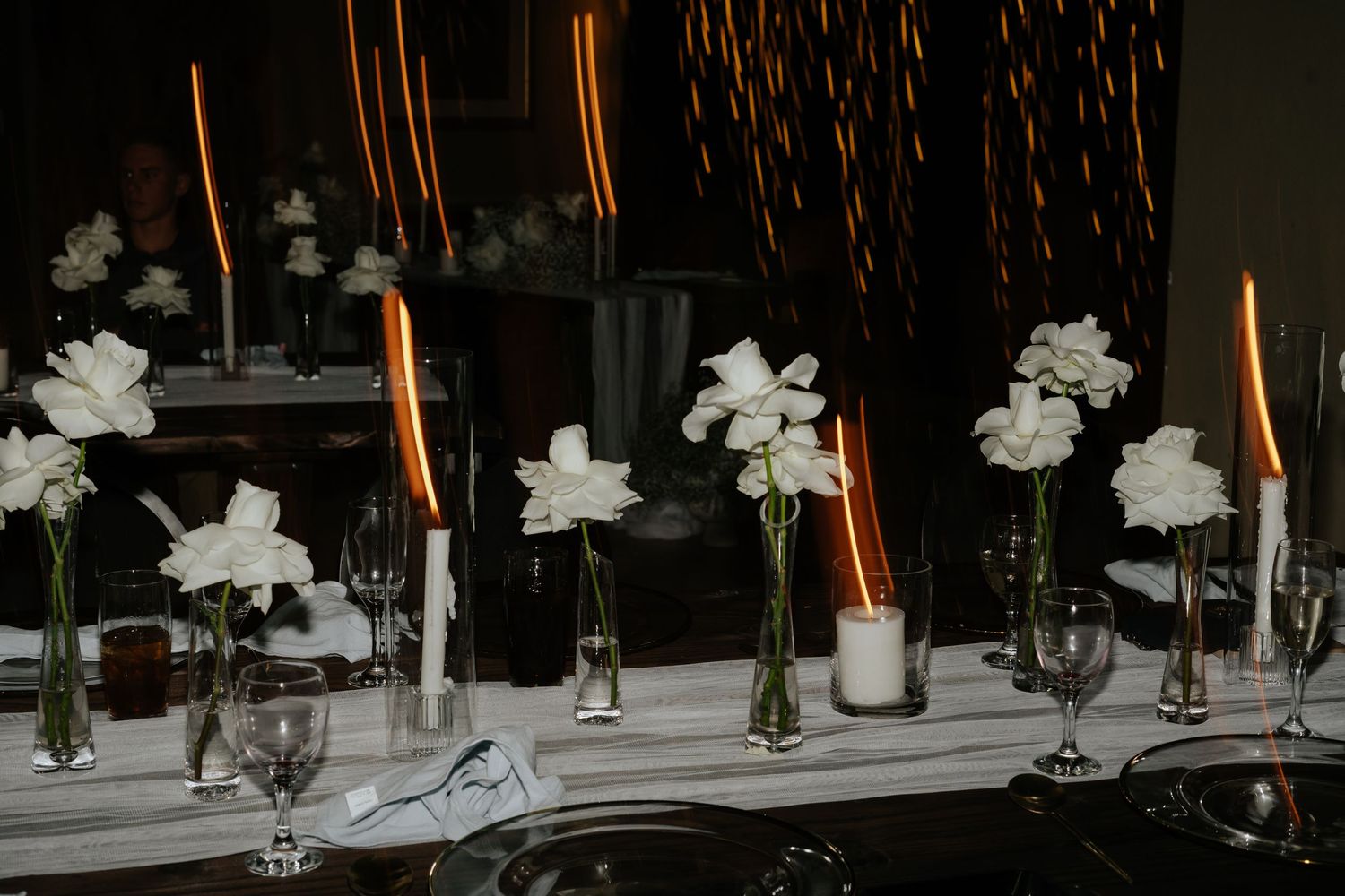 Elegant wedding reception table with white floral centerpieces and tall candles.