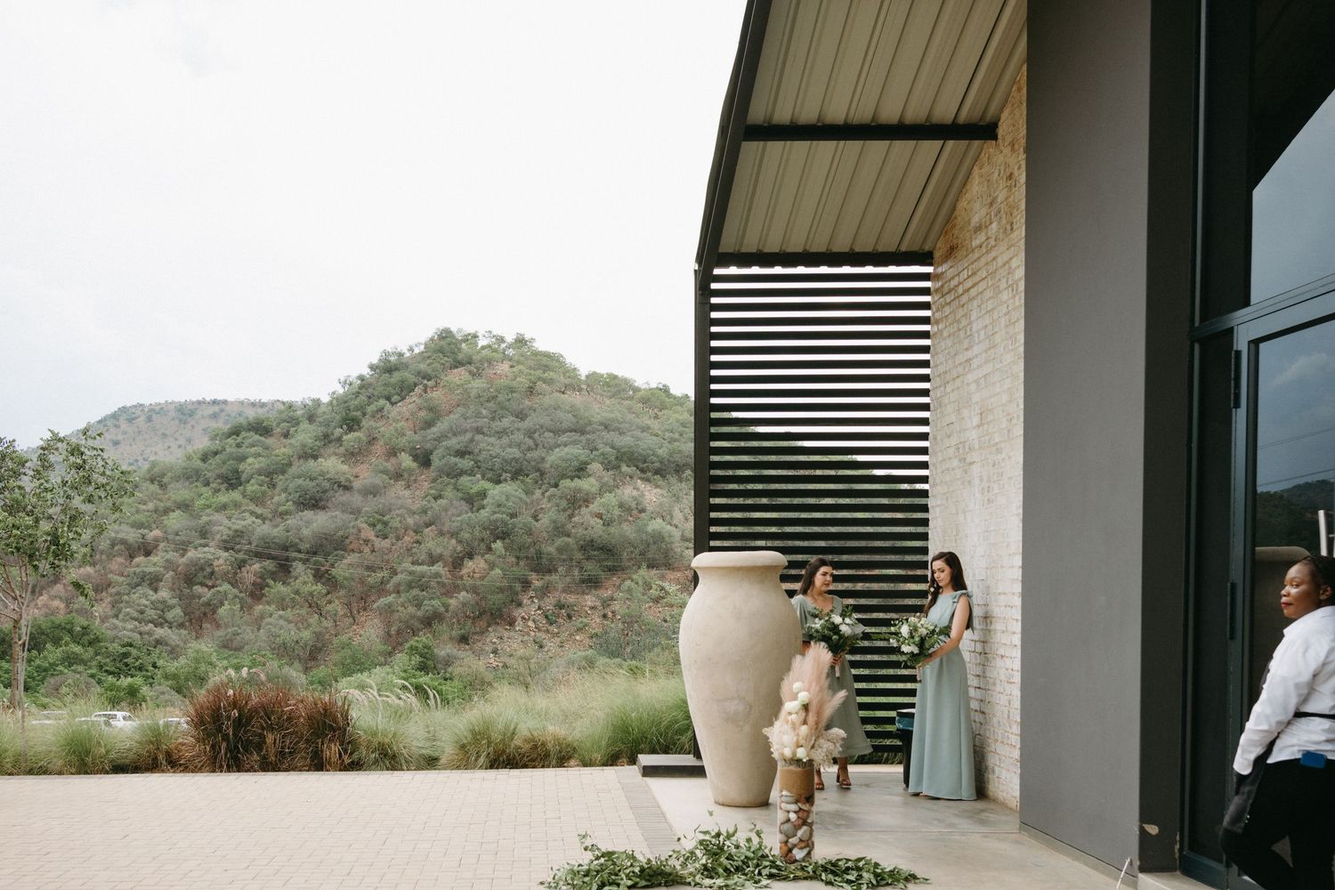 Two people standing on a modern patio with a sleek wood slat feature and mountain views in the background.