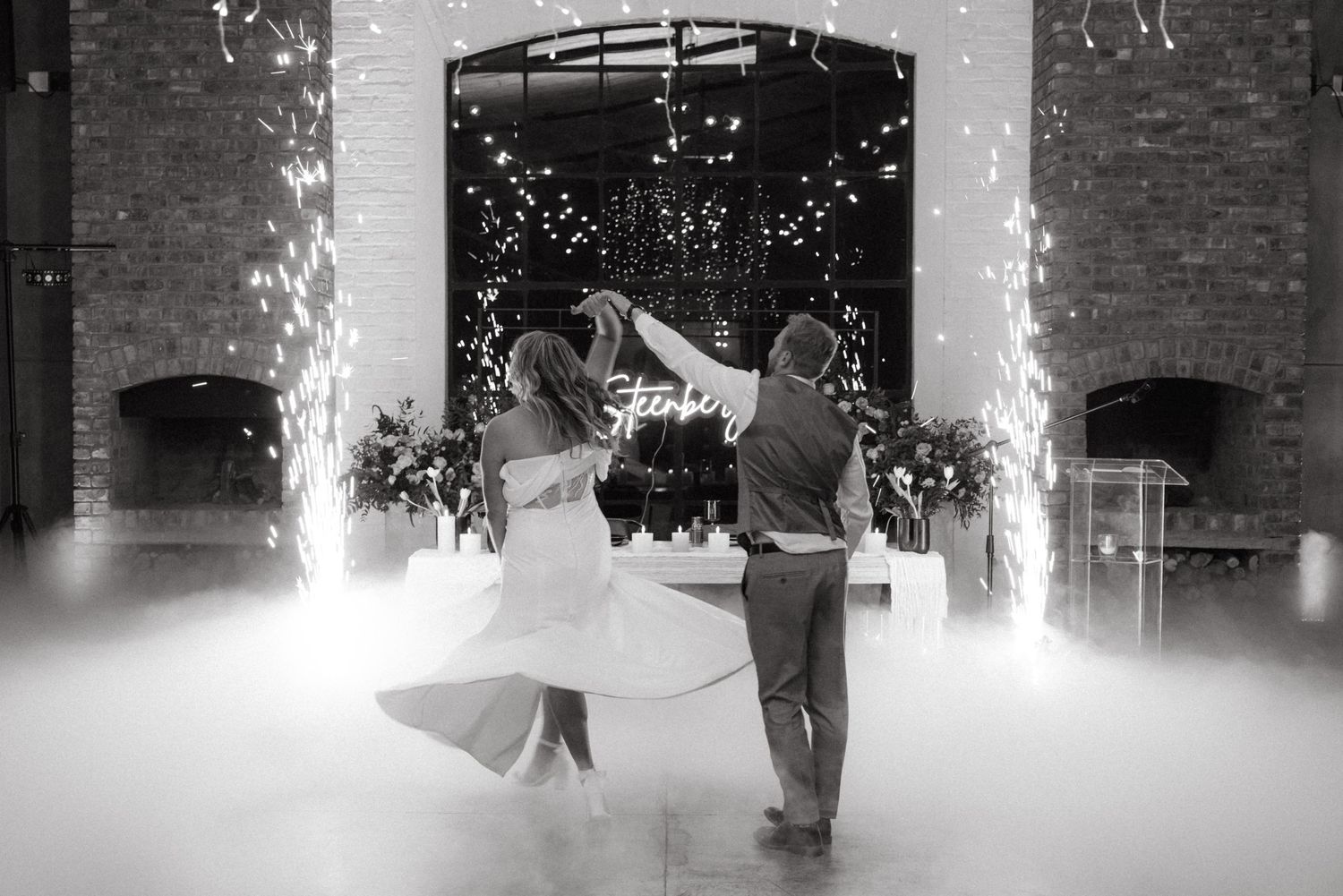 Couple dances surrounded by fog and sparklers at wedding reception.
