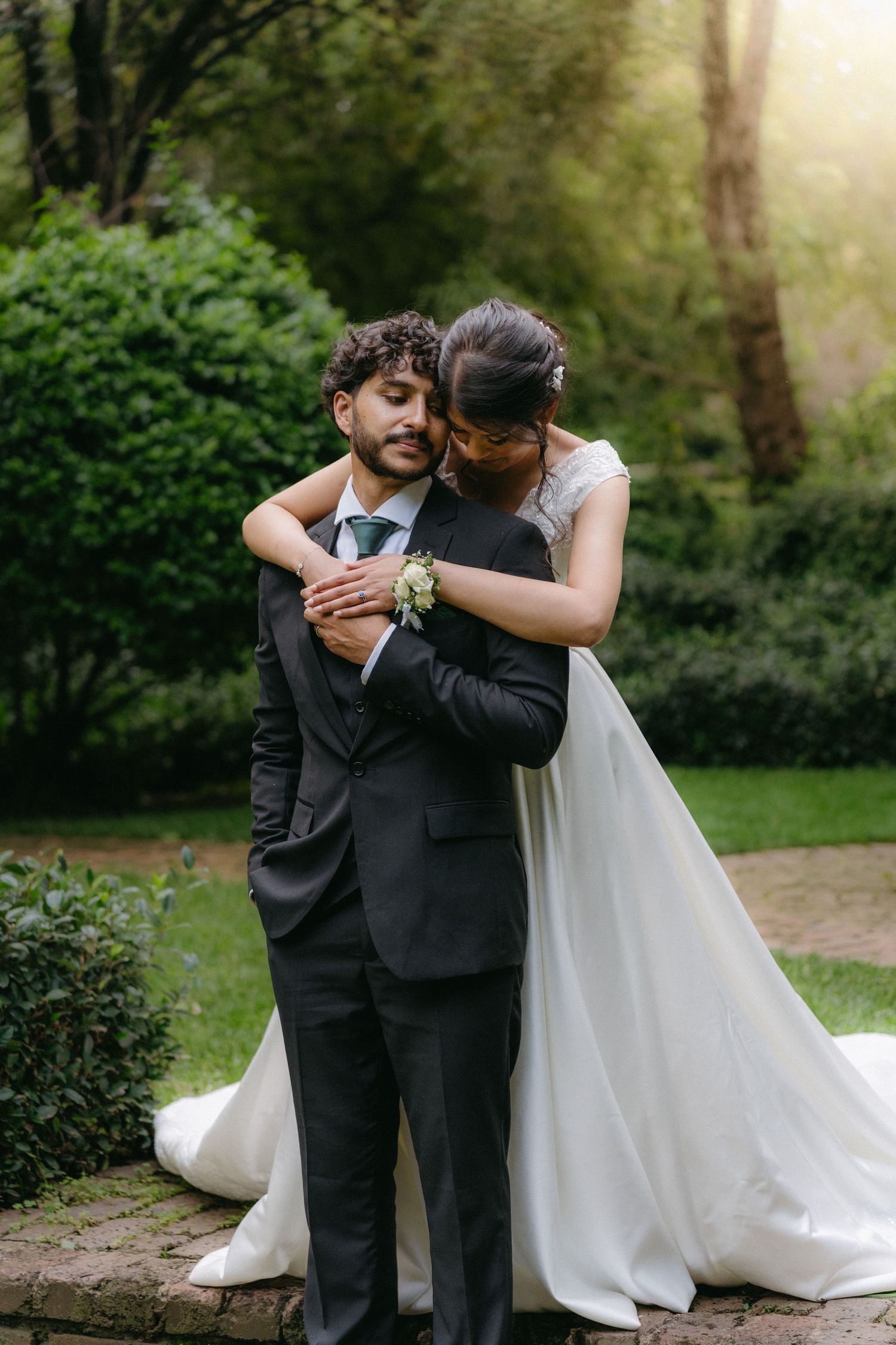 Golden hour wedding portraits in a lush garden setting capture intimate moments between newlyweds.